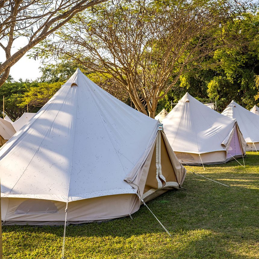Tiendas de glamping Amatista en el pasto bajo los árboles