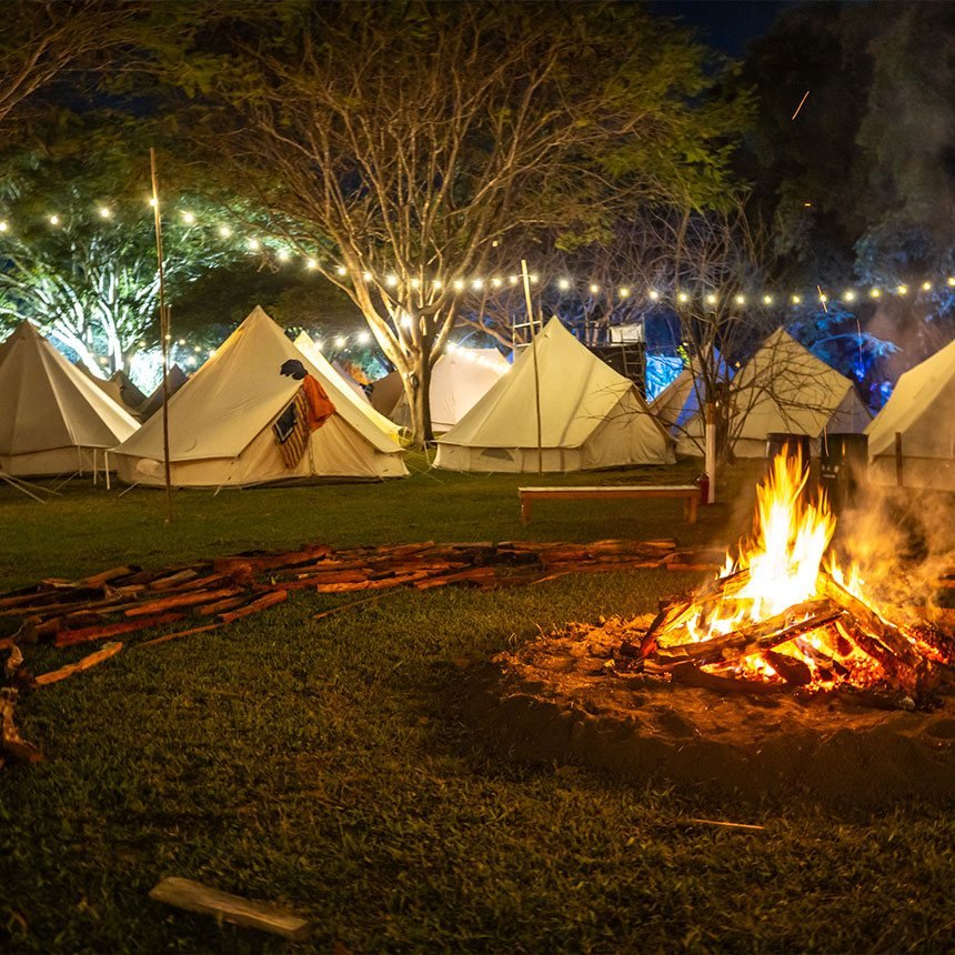 Tiendas de campaña blancas iluminadas con una fogata al frente, de noche