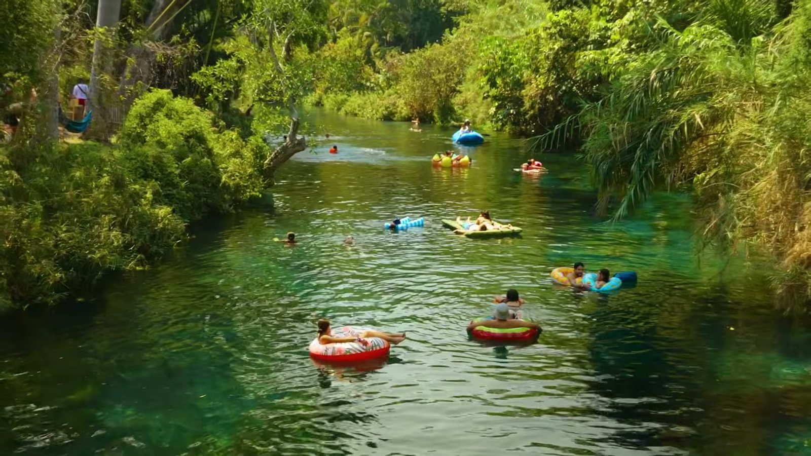 Gente flotando en llantas por el río transparente de Las Estacas entre la vegetación