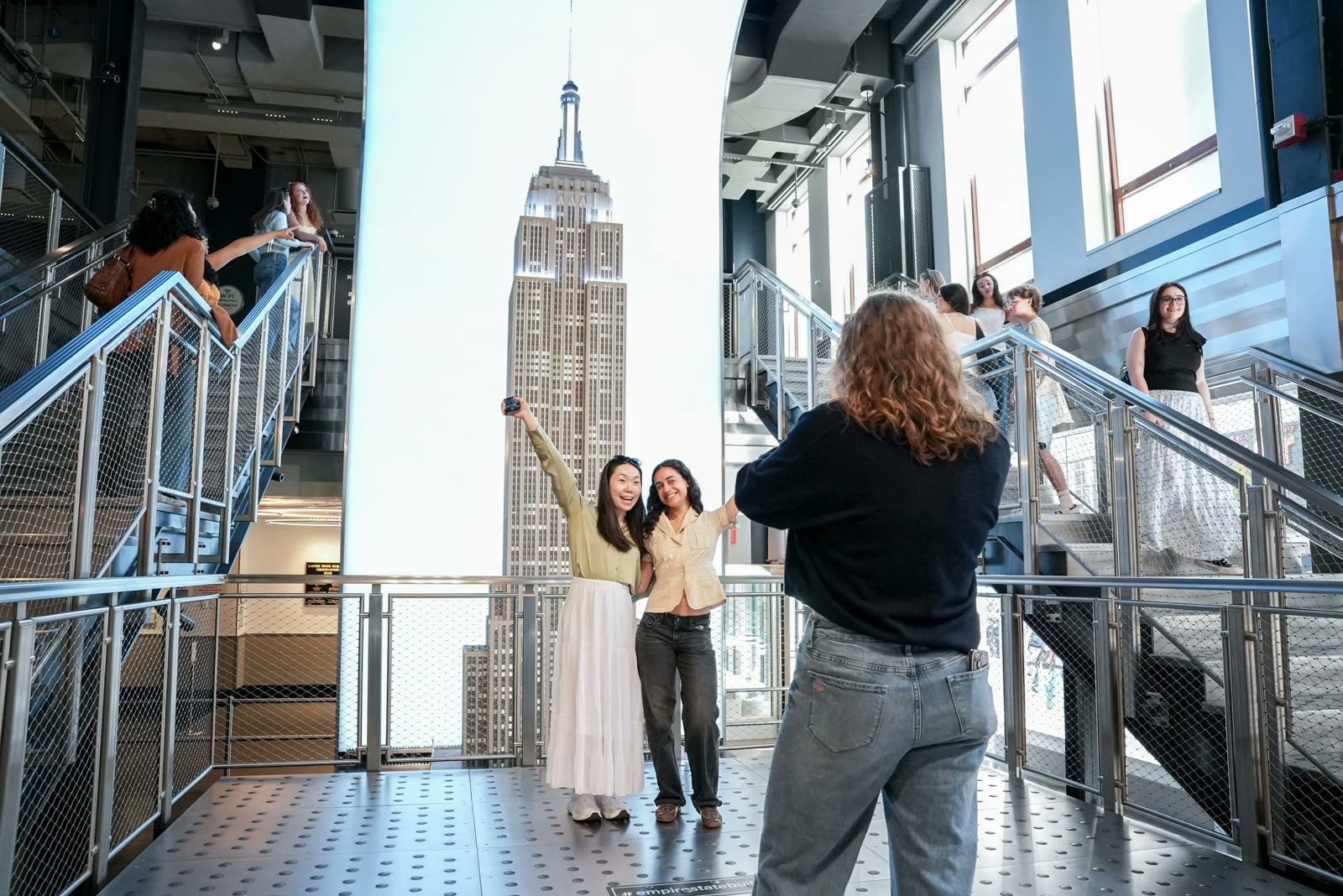 Visitantes en una escalera frente a una imagen gigante del Empire State