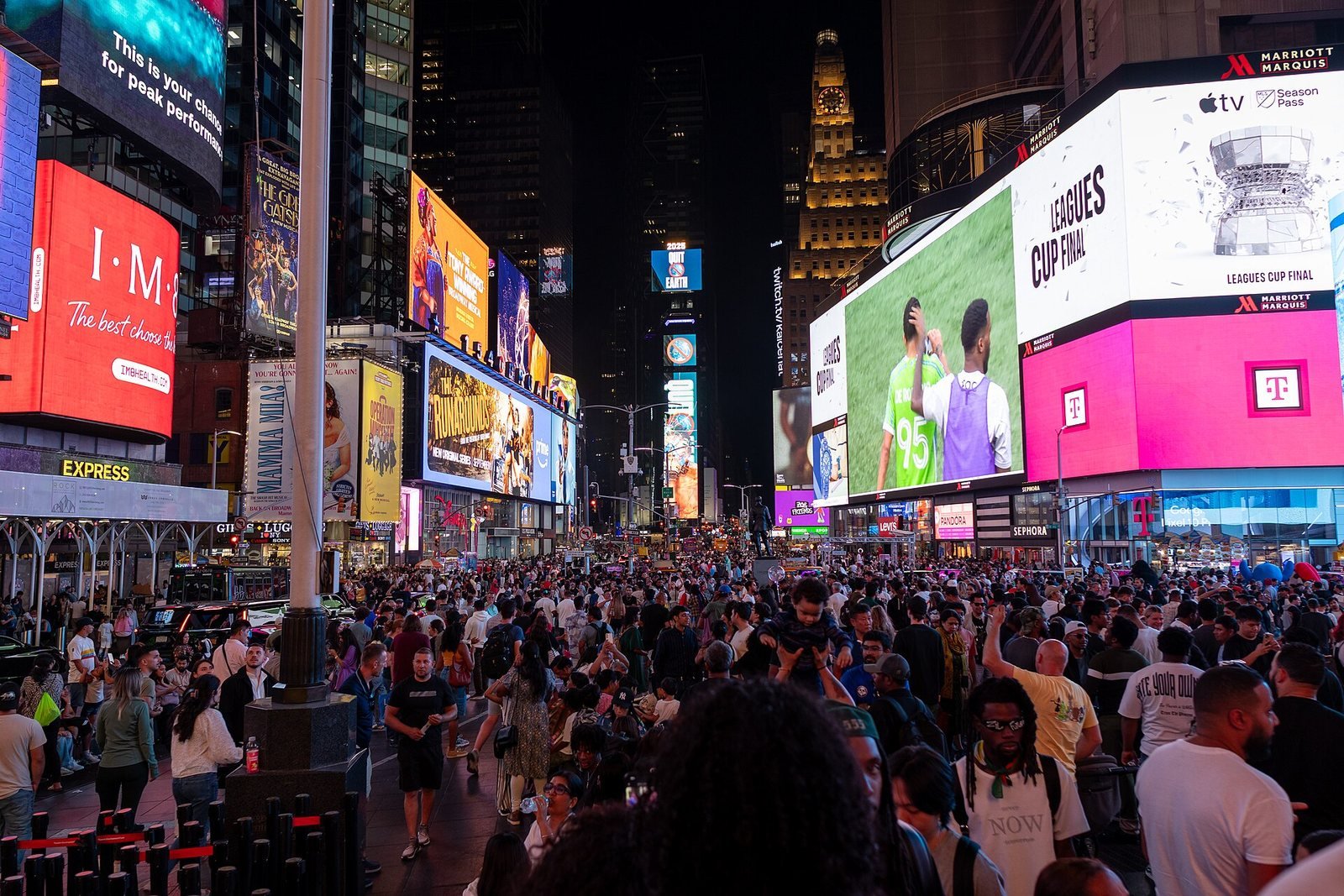 Times Square de noche, con pantallas gigantes y la plaza llena de gente