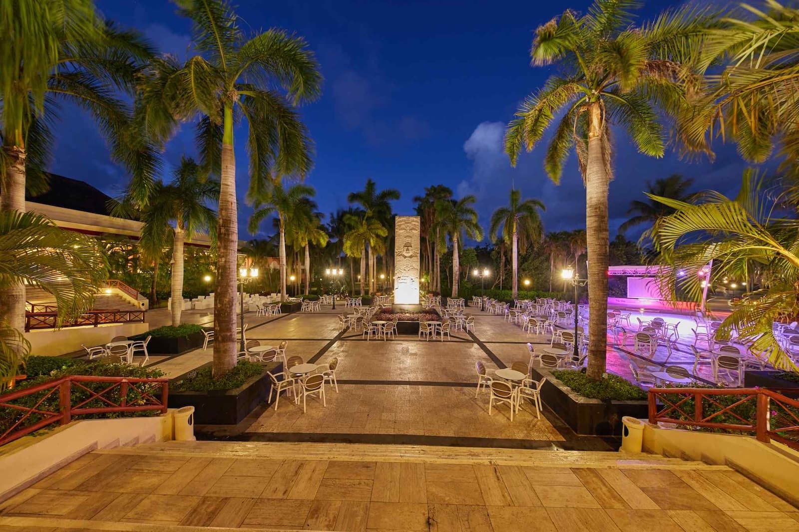 La terraza del lobby iluminada de noche entre palmeras