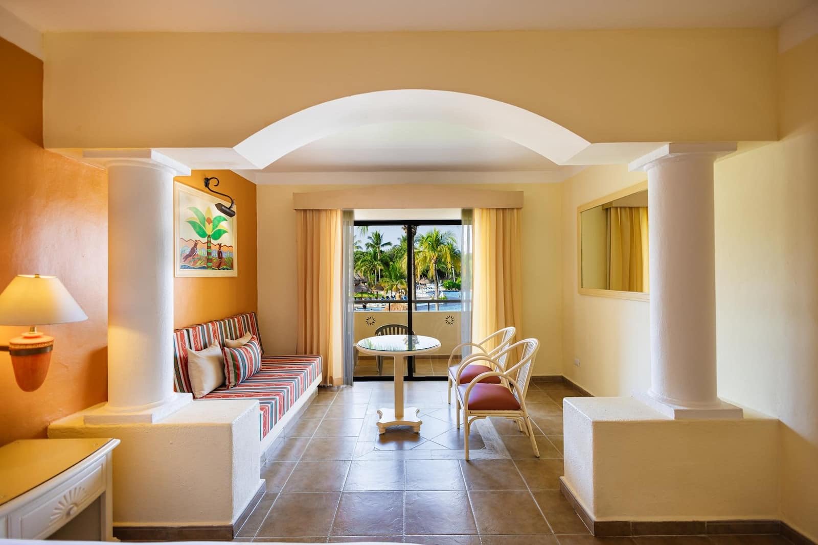 La sala de una Junior Suite con sillones de rayas y arcos blancos