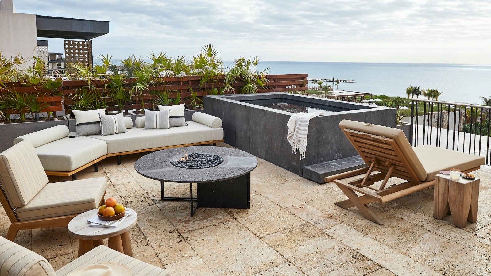 Azotea de un penthouse con jacuzzi, sillones y fogatero frente al mar