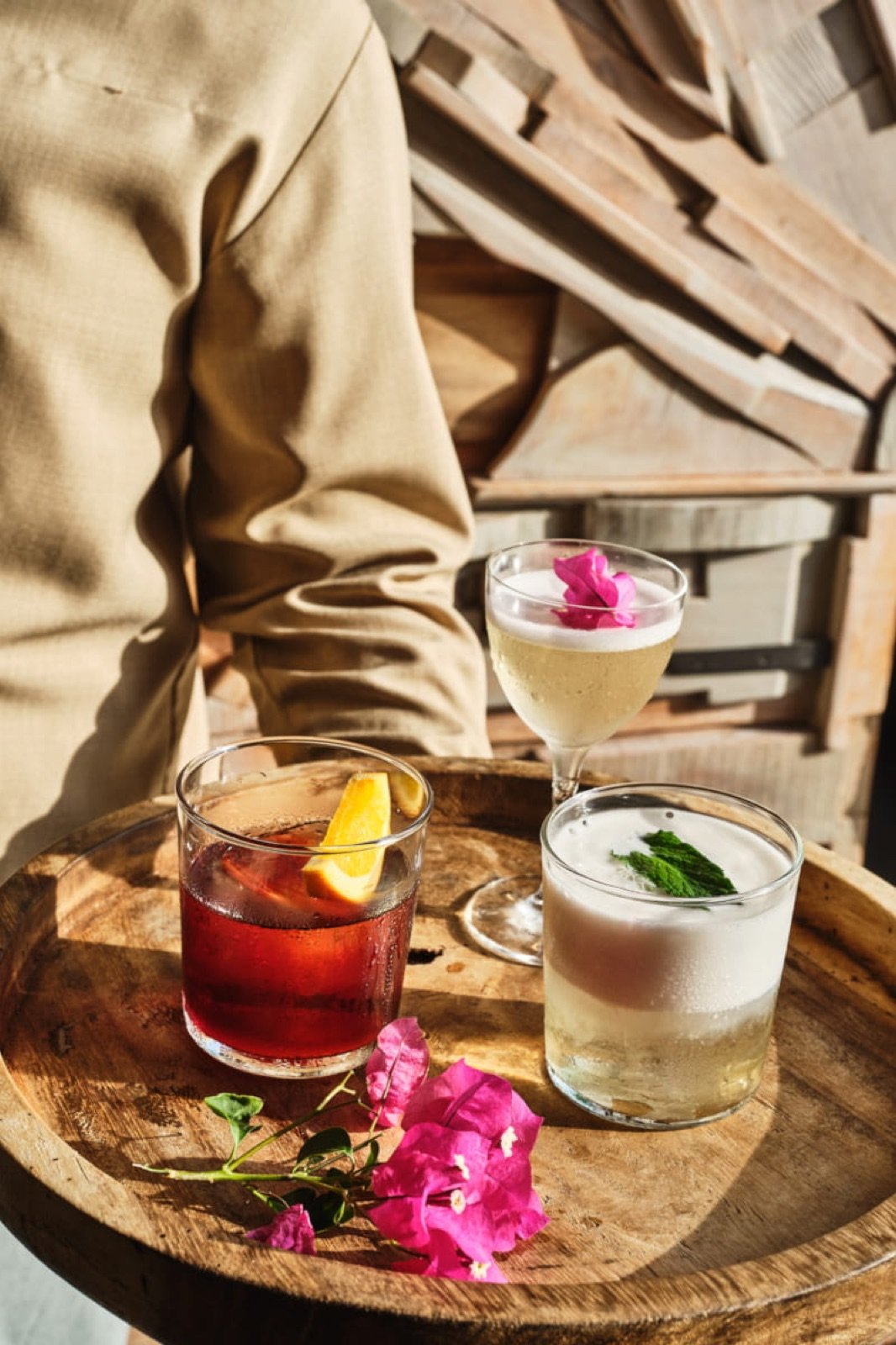Tres cócteles con flores y hierbas sobre una barra de madera