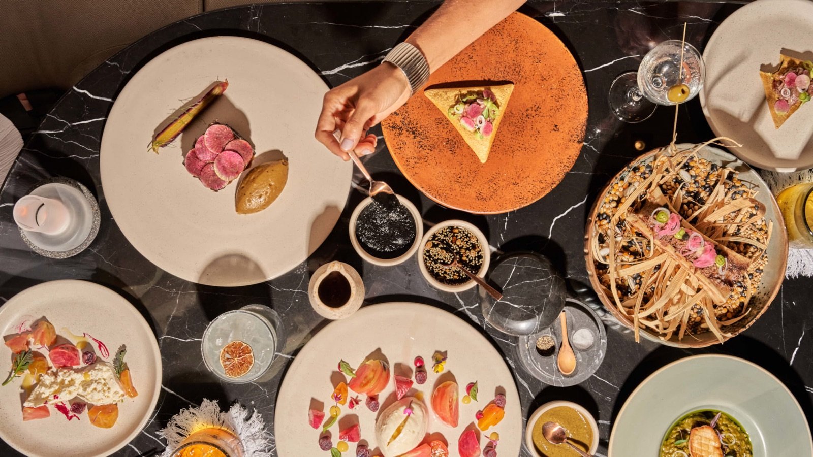 Mesa con platillos mexicanos de autor, flores y copas de vino