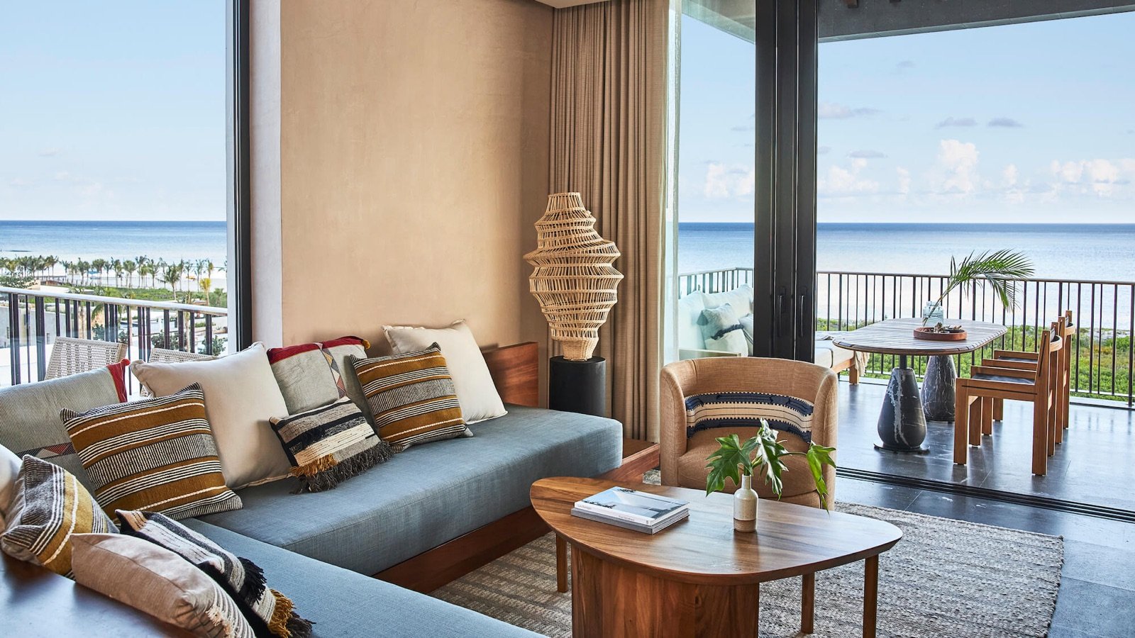 Sala de una suite con sillones claros y ventanal abierto al mar