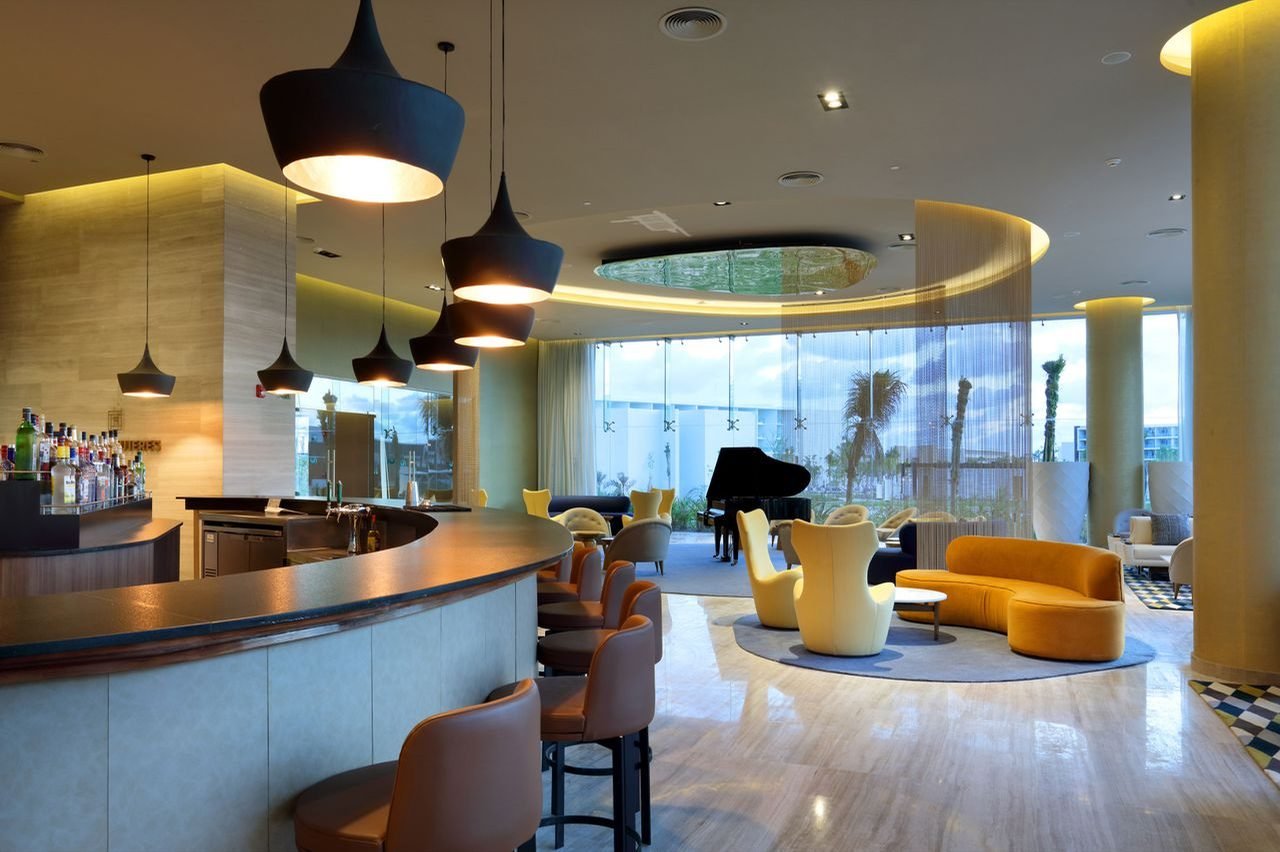Bar del lobby con piano y sillones naranjas