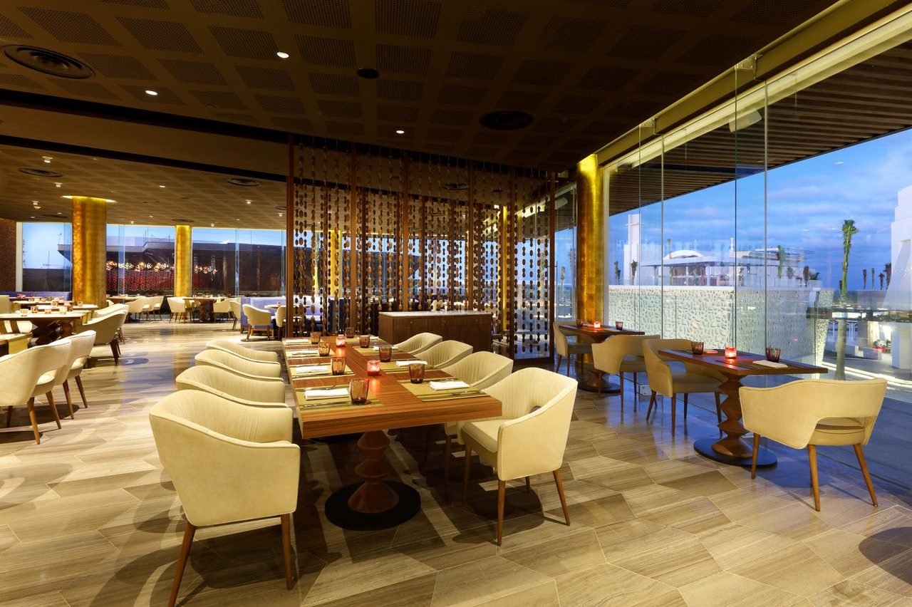Restaurante con sillones dorados y ventanales