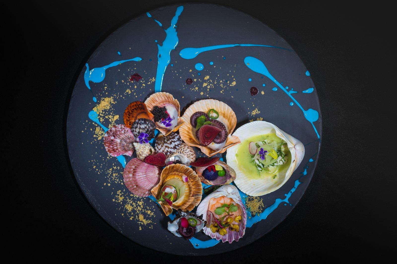Platillo de autor con mariscos sobre un plato oscuro