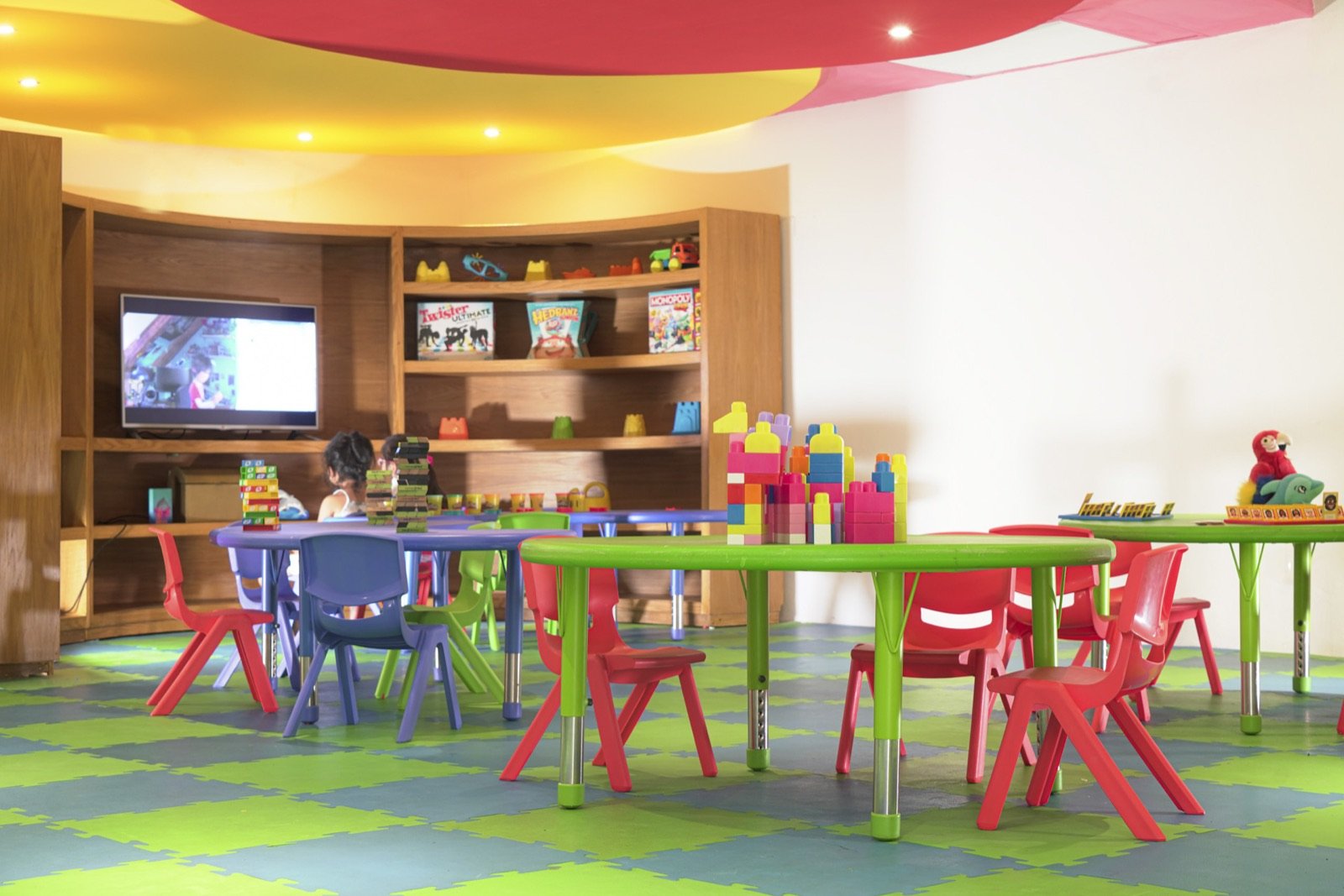 Área infantil del Kamp Krystal con mesas y juguetes de colores