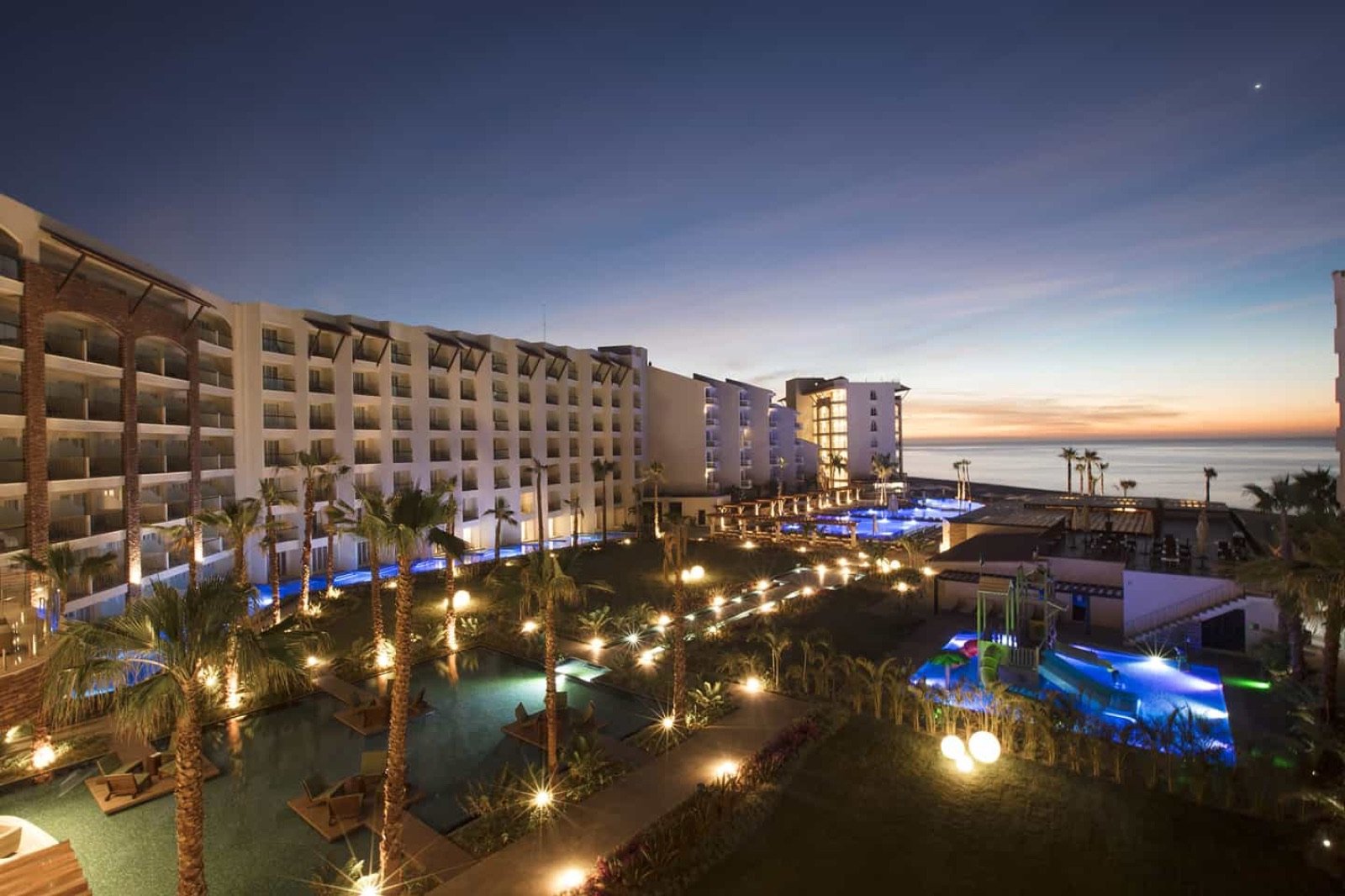 El hotel iluminado de noche, con las albercas