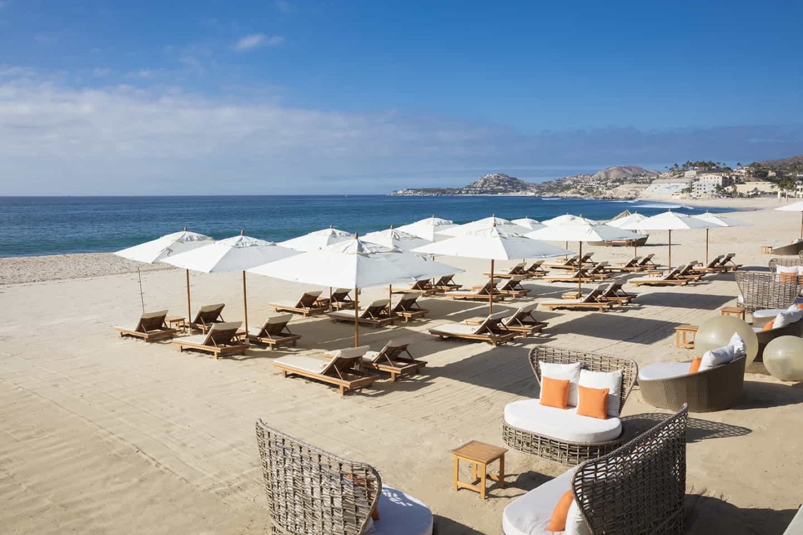Camastros y sombrillas blancas en la playa del hotel