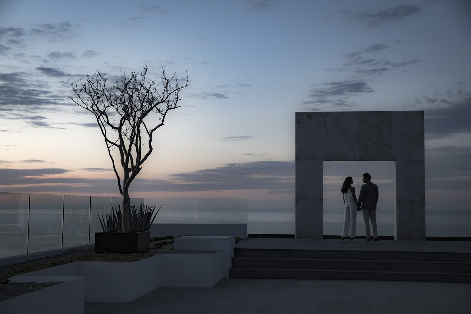 Silueta de una pareja bajo un arco de piedra al atardecer