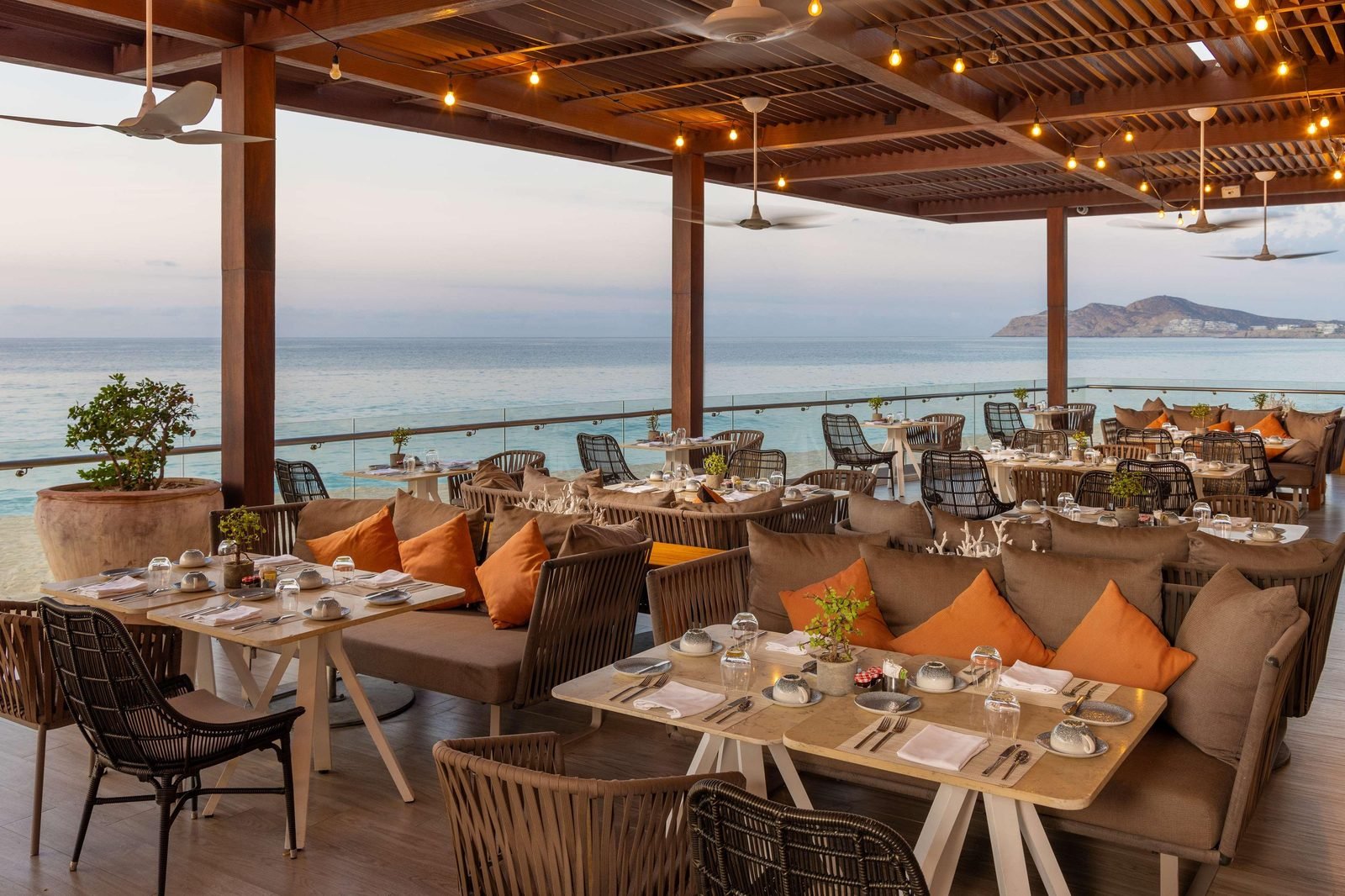 Terraza de restaurante con mesas frente al mar