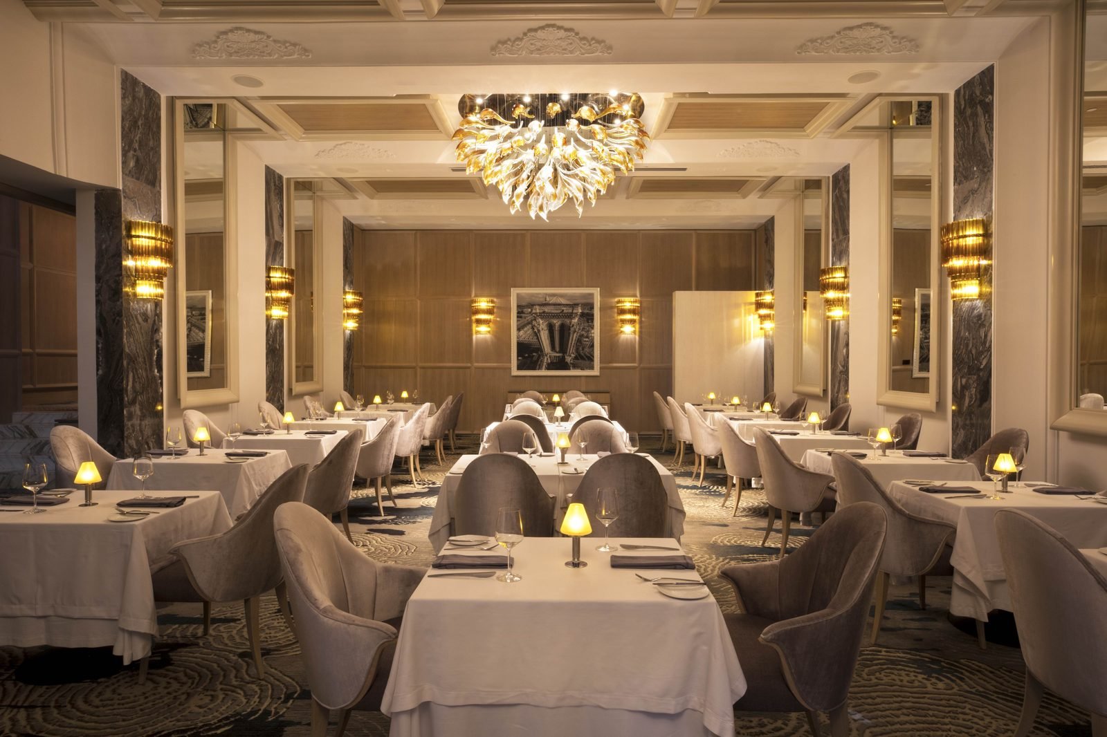 Comedor elegante con candelabro y mesas con mantel blanco