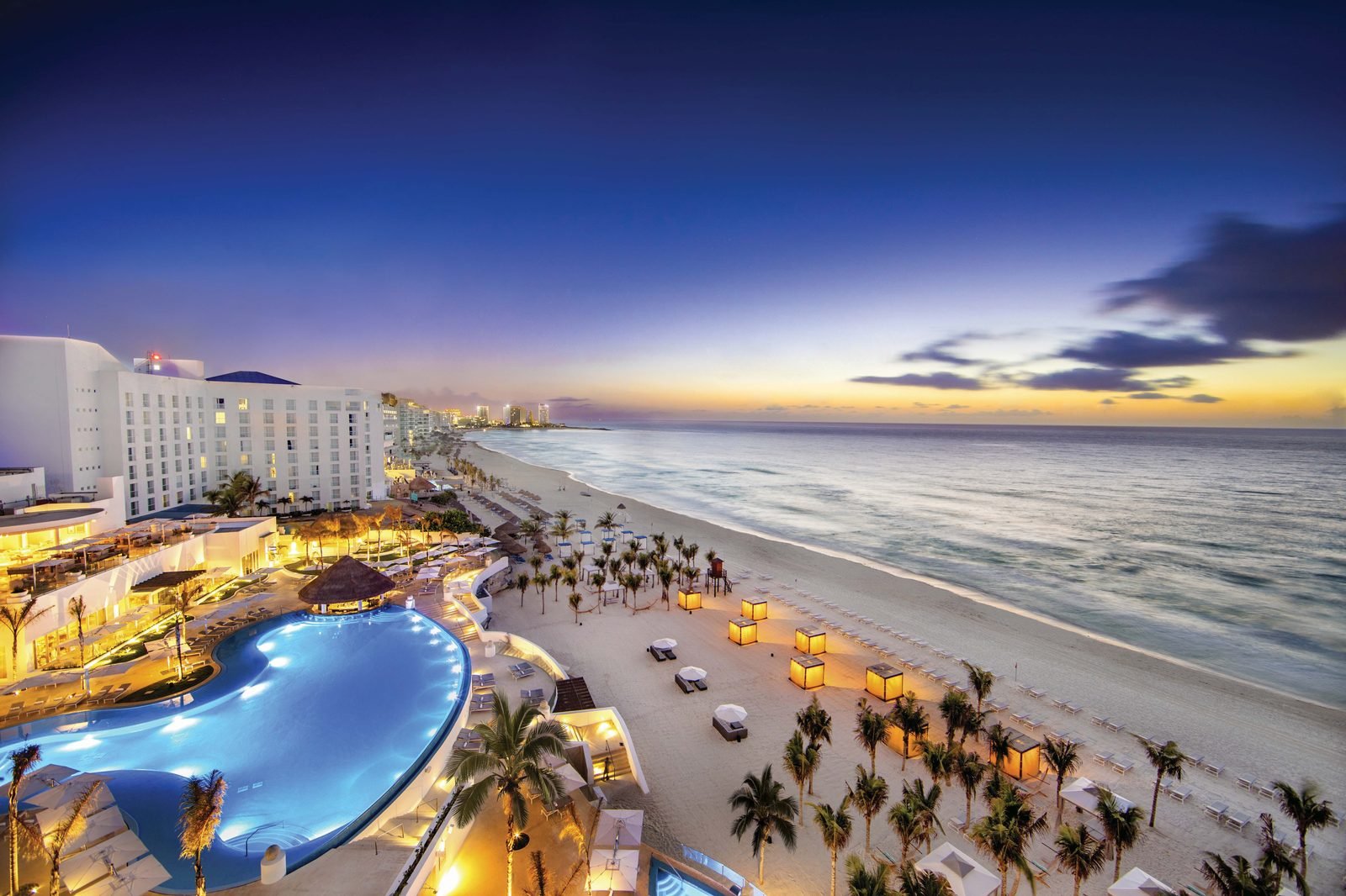 Le Blanc al atardecer, con sus albercas iluminadas y la Zona Hotelera al fondo