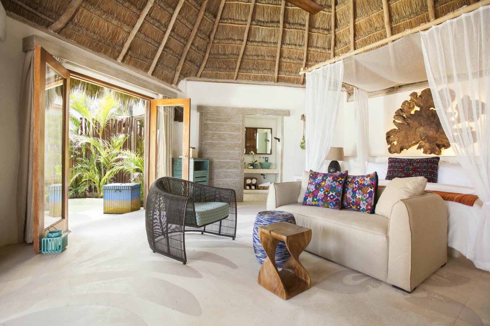 Habitación Ocean Front con techo de palma, cama con dosel y sala