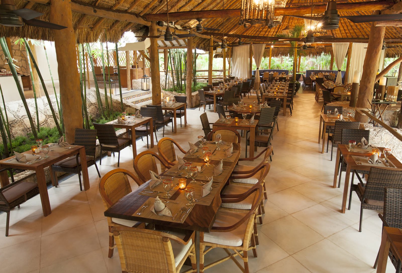 Restaurante bajo un techo de palma con mesas de madera
