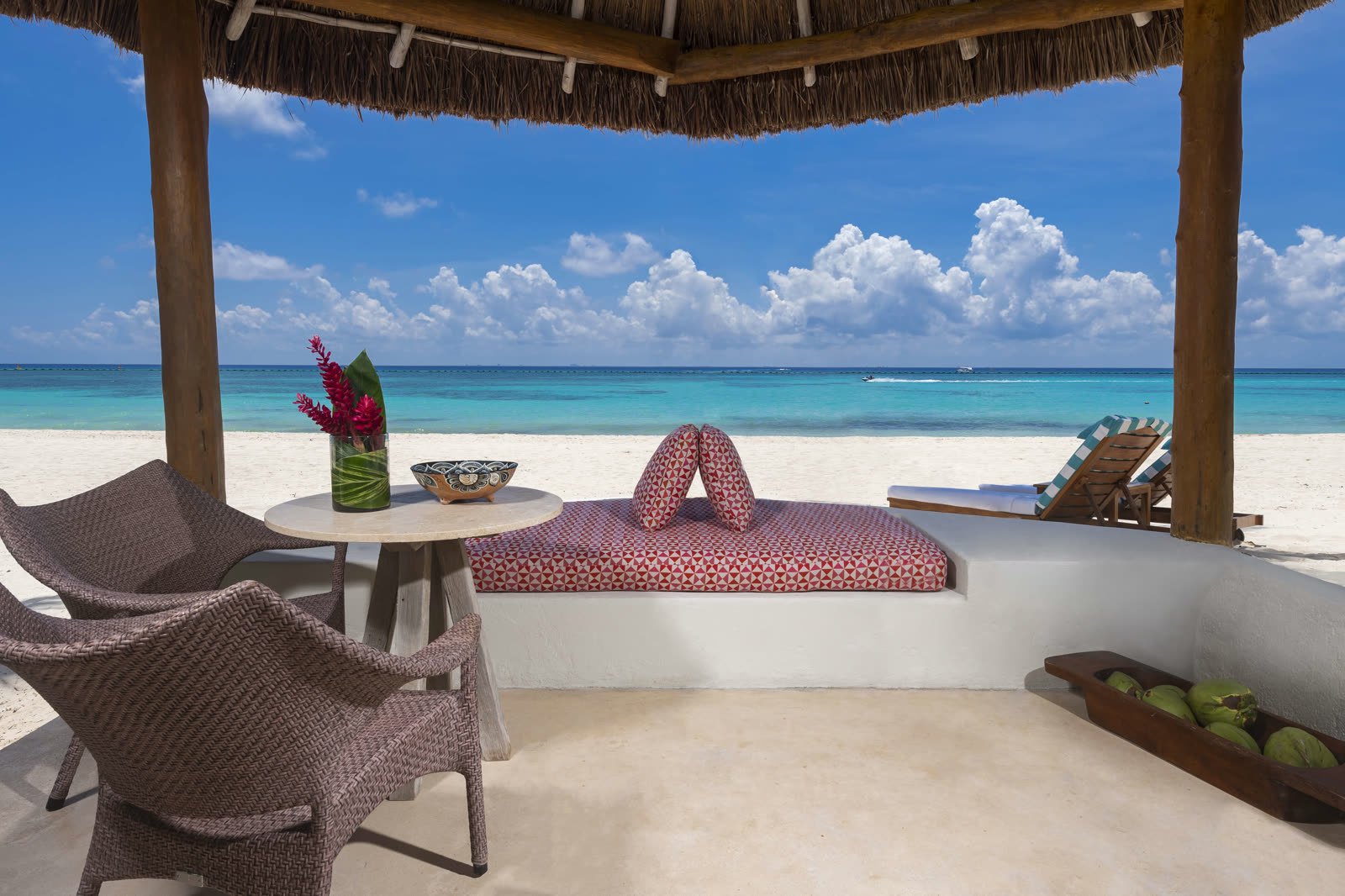 Terraza frente al mar con sillones y la playa enfrente