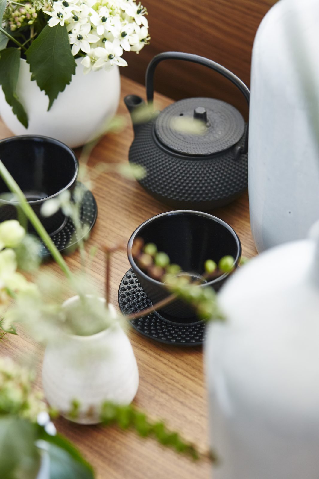 Juego de té de hierro y flores blancas sobre una mesa de madera