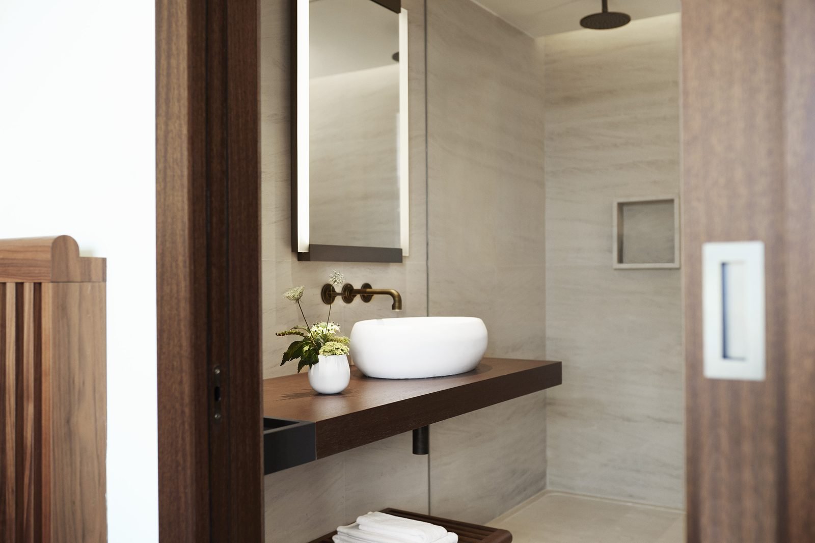 Baño de mármol claro con lavabo de piedra y regadera