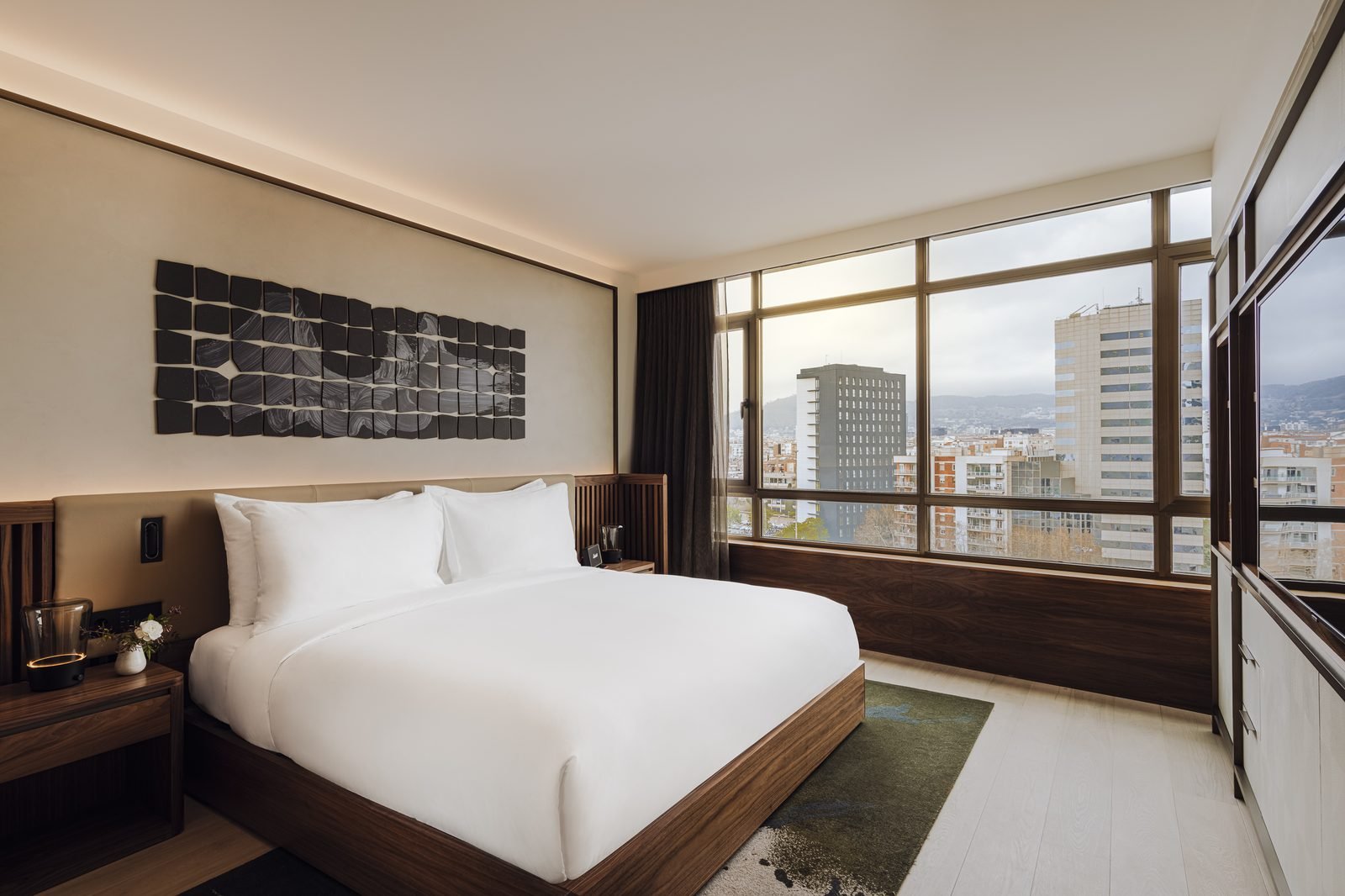 Habitación Deluxe City con cama king y ventanales a la ciudad