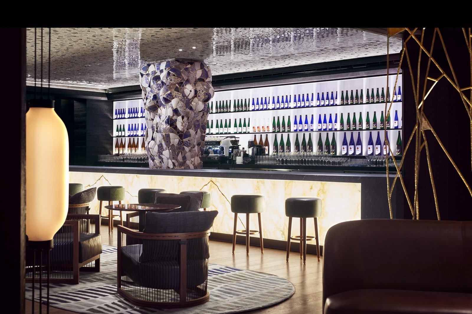 La barra del Nobu Bar con botellas de sake iluminadas y bancos altos