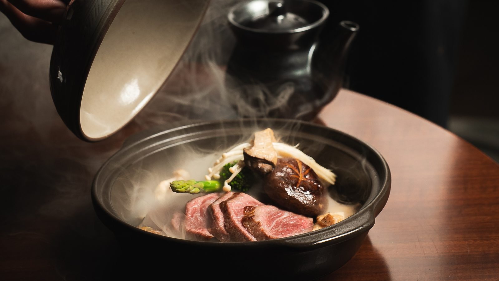 Un plato de carne con vapor que se destapa frente al comensal