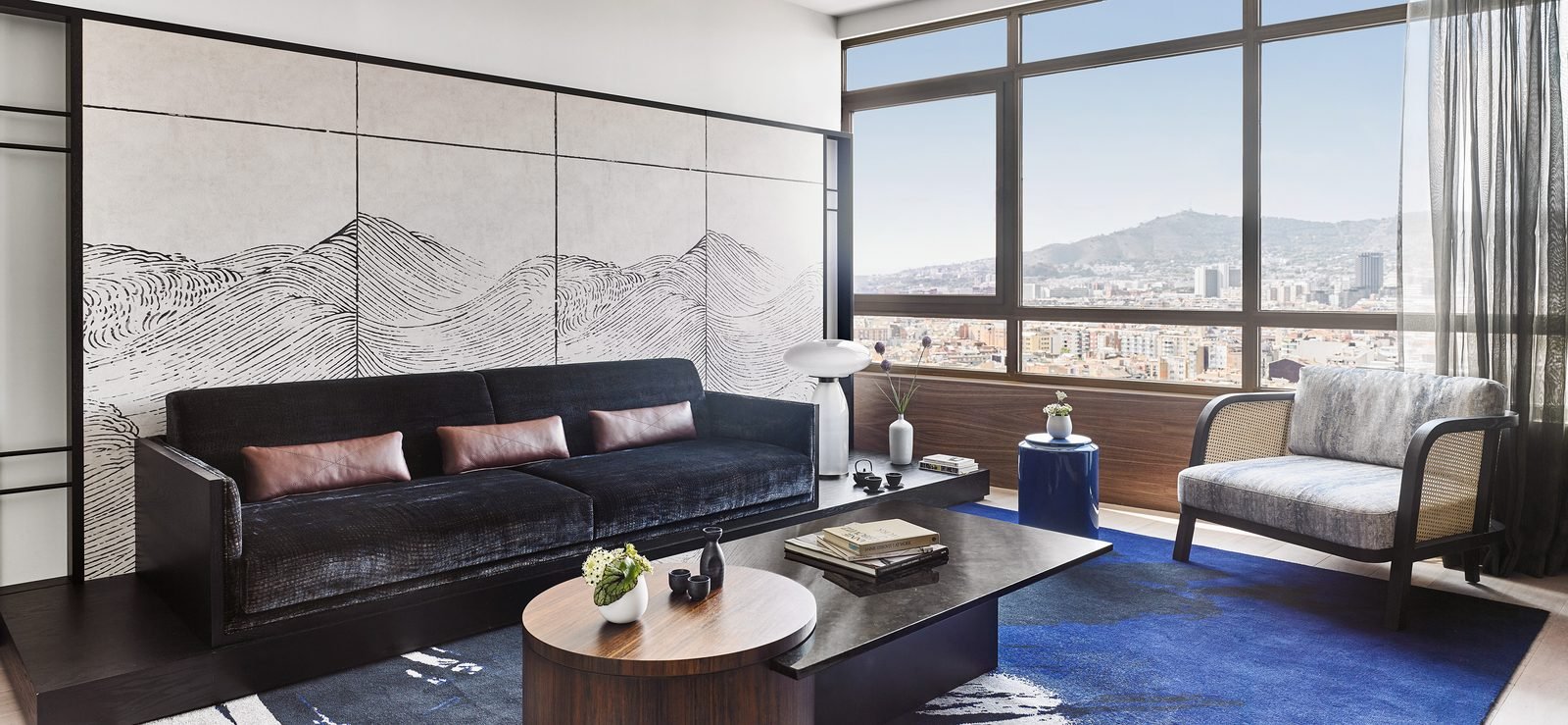 Sala de la Suite Sake con sillones, mural de montañas y vista a la ciudad