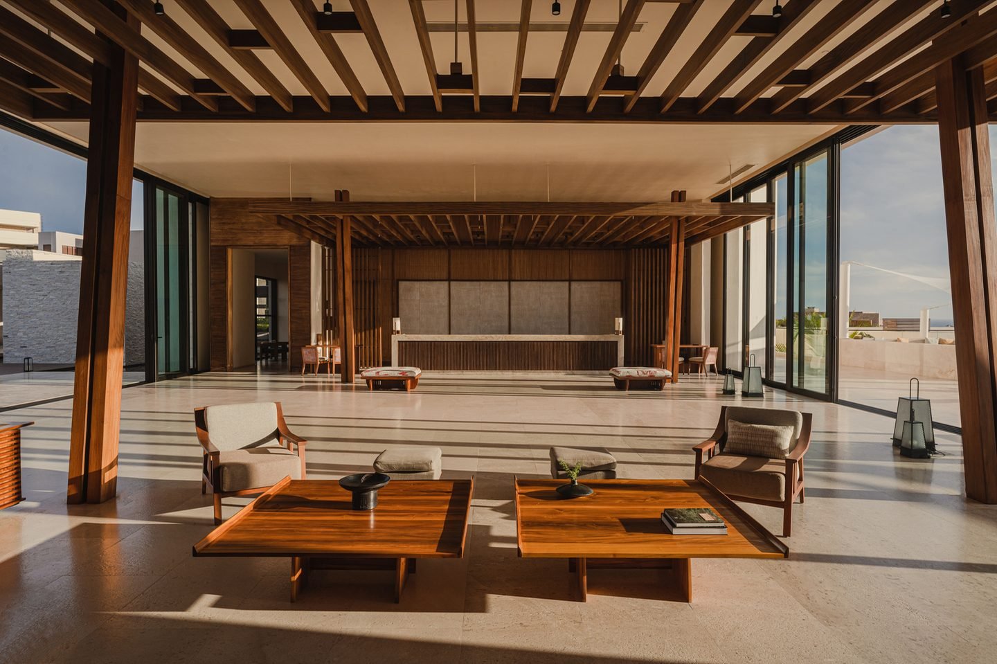 Lobby abierto de madera con sillones bajos y vista al mar