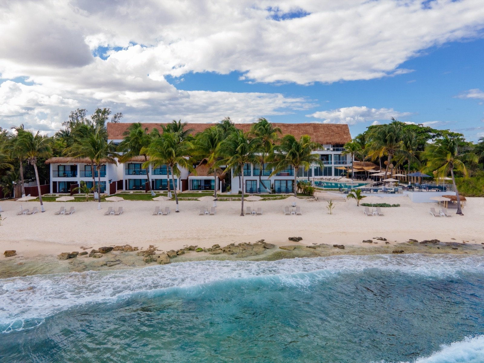El hotel visto desde el mar, con la playa y la selva detrás