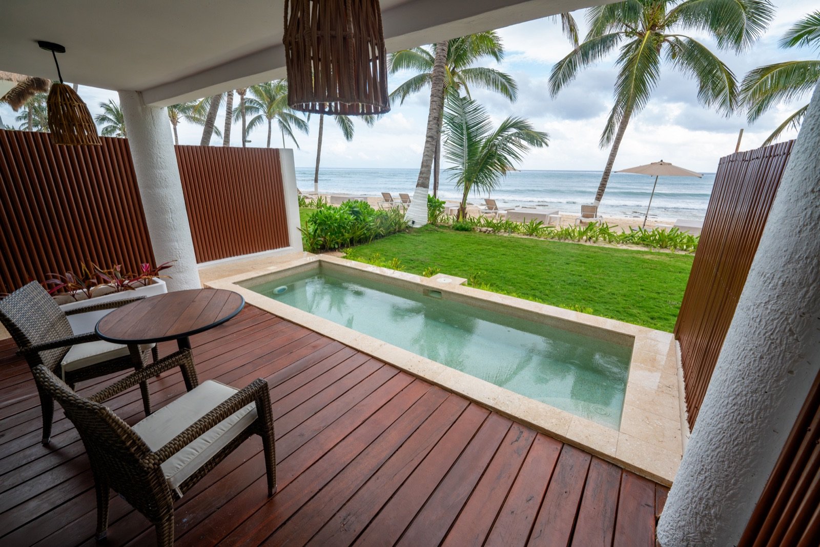 Terraza de madera con alberca privada, camastros y el mar al fondo