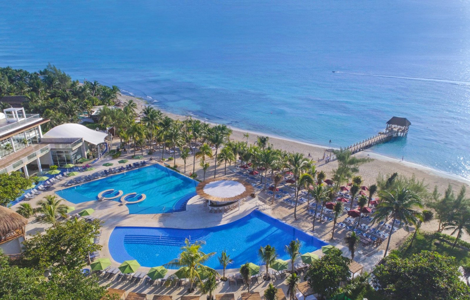 Vista aérea del resort, con sus albercas azules entre la selva y la playa al fondo