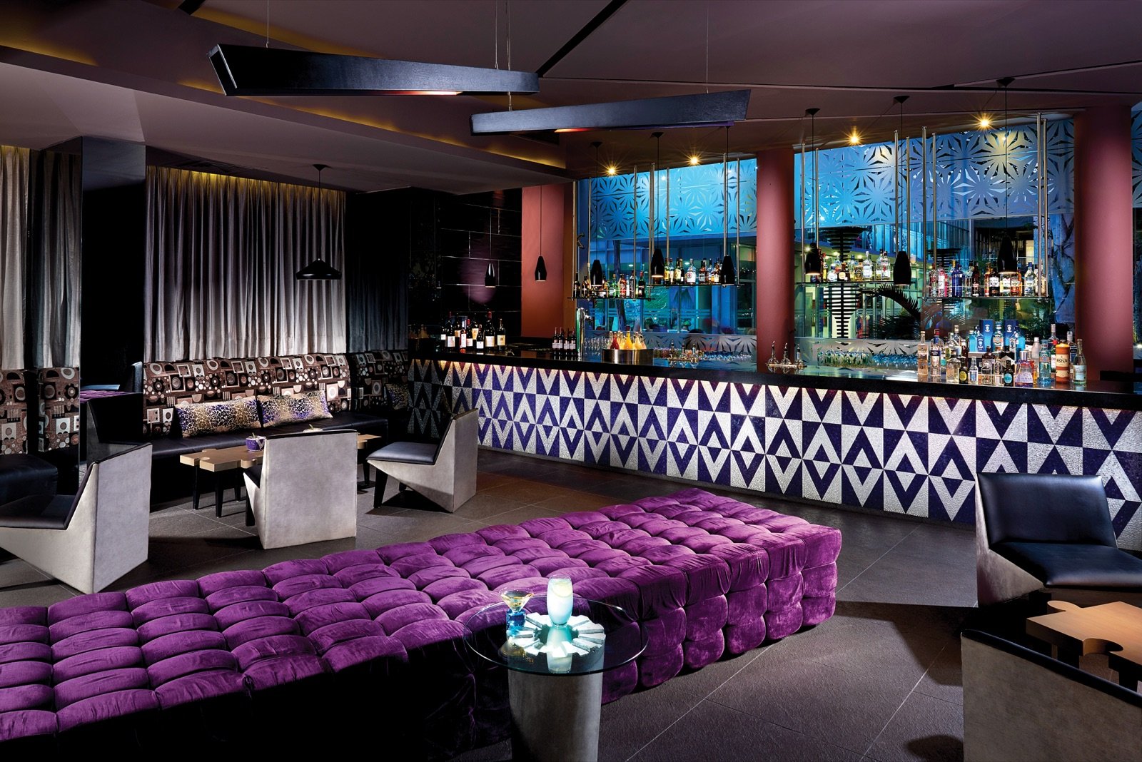 The Gin Bar con su barra iluminada y sillones morados