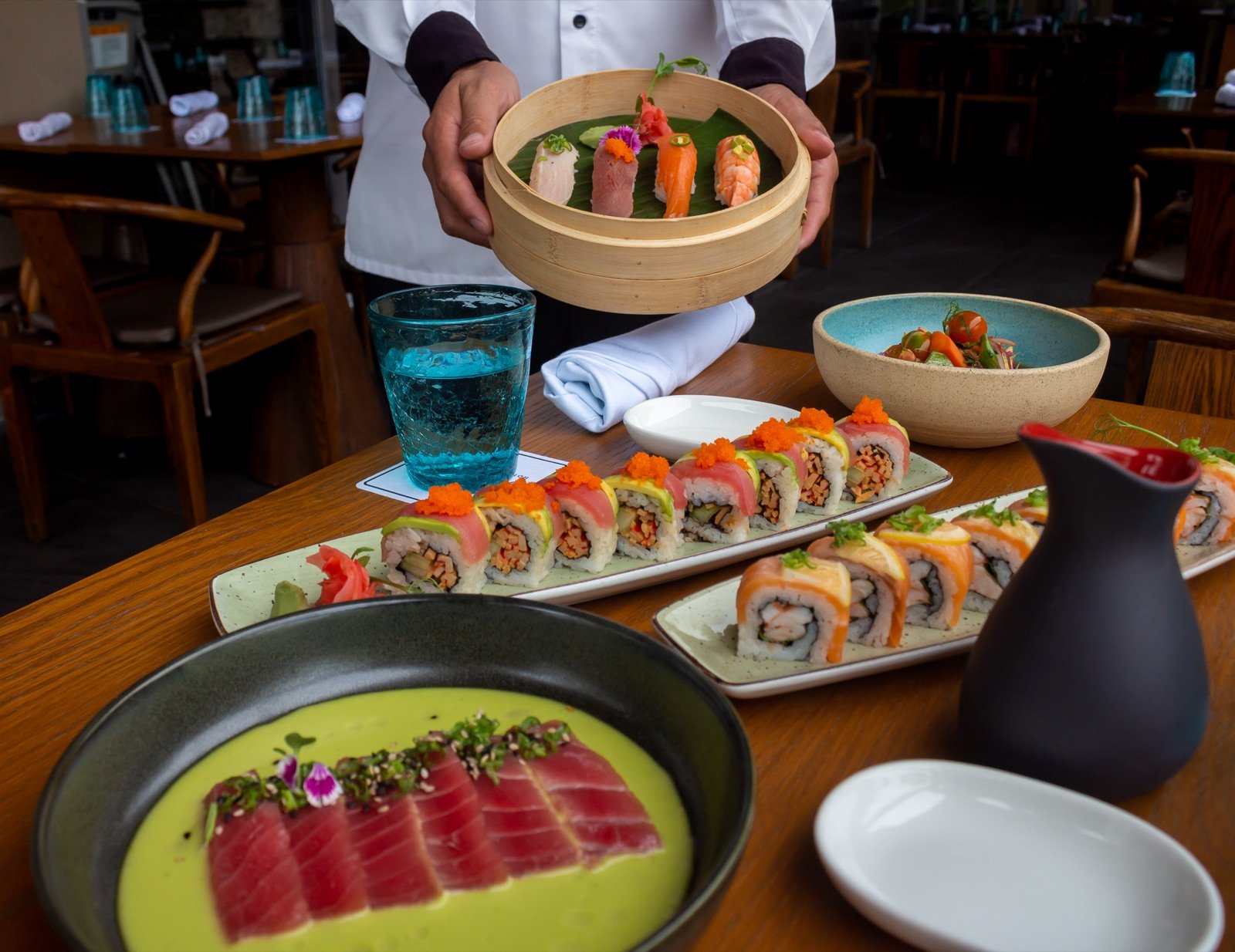 Rollos de sushi, sashimi y una canasta de dim sum en Oka