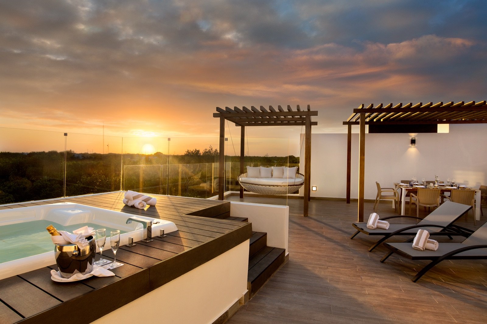 Azotea privada de un penthouse al atardecer, con jacuzzi y camastros