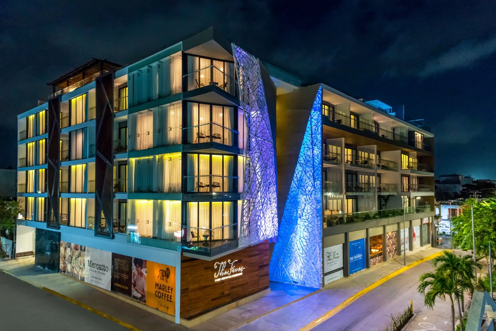 La fachada del hotel de noche, con luces azules