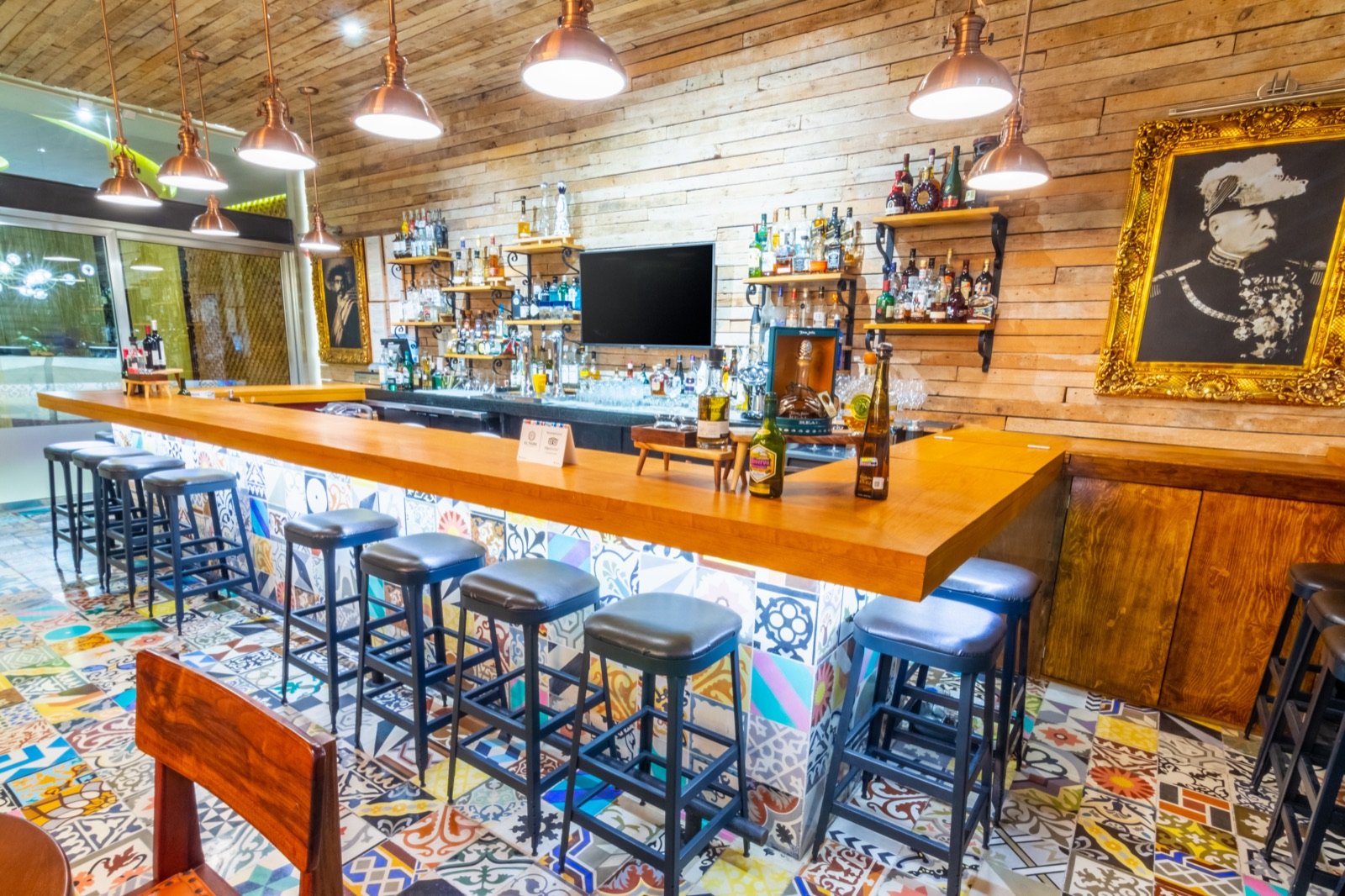 La barra de madera de El Tigre con bancos azules y piso de mosaico de colores