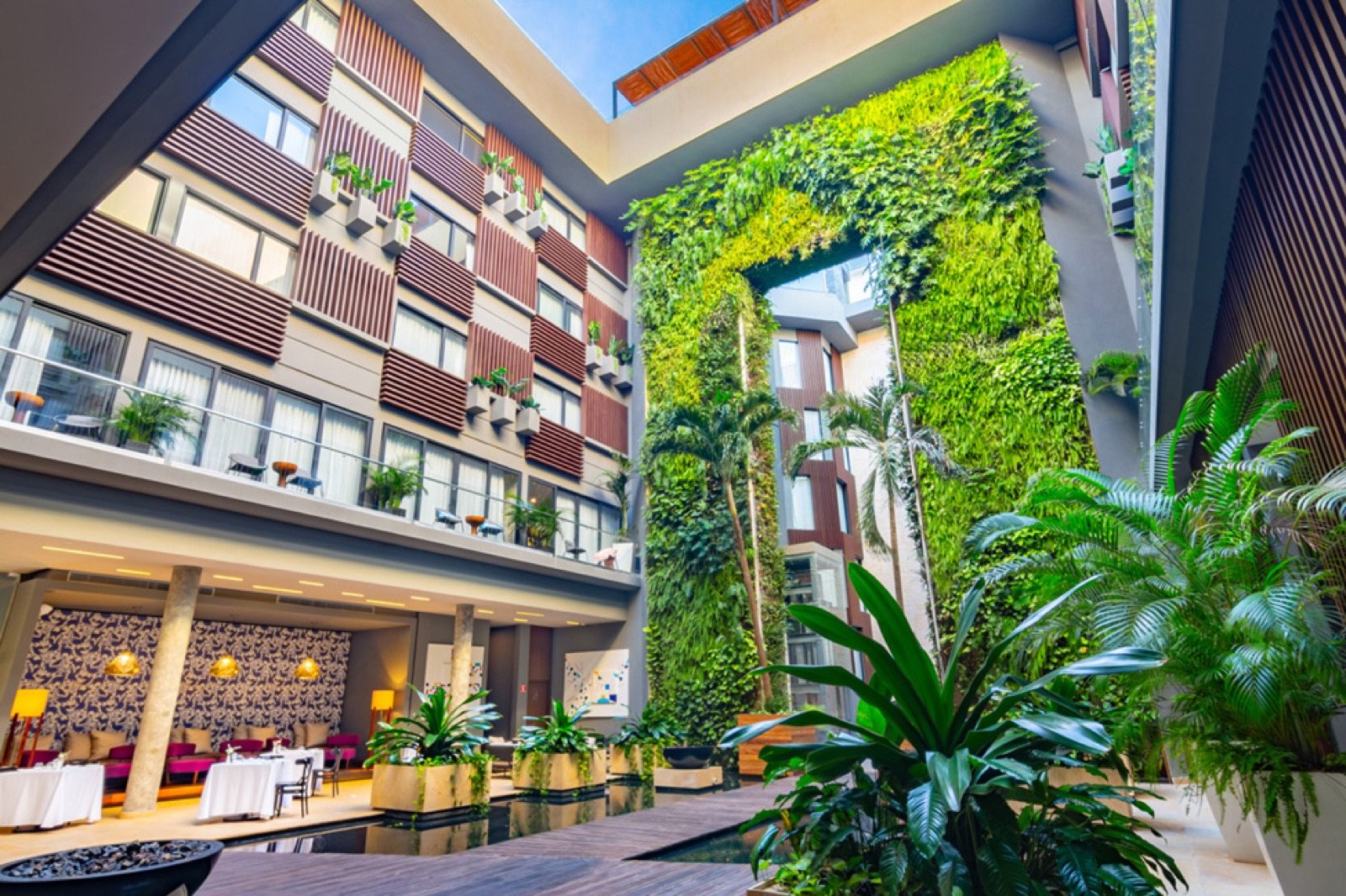 El patio interior del hotel con un muro verde de plantas y un espejo de agua