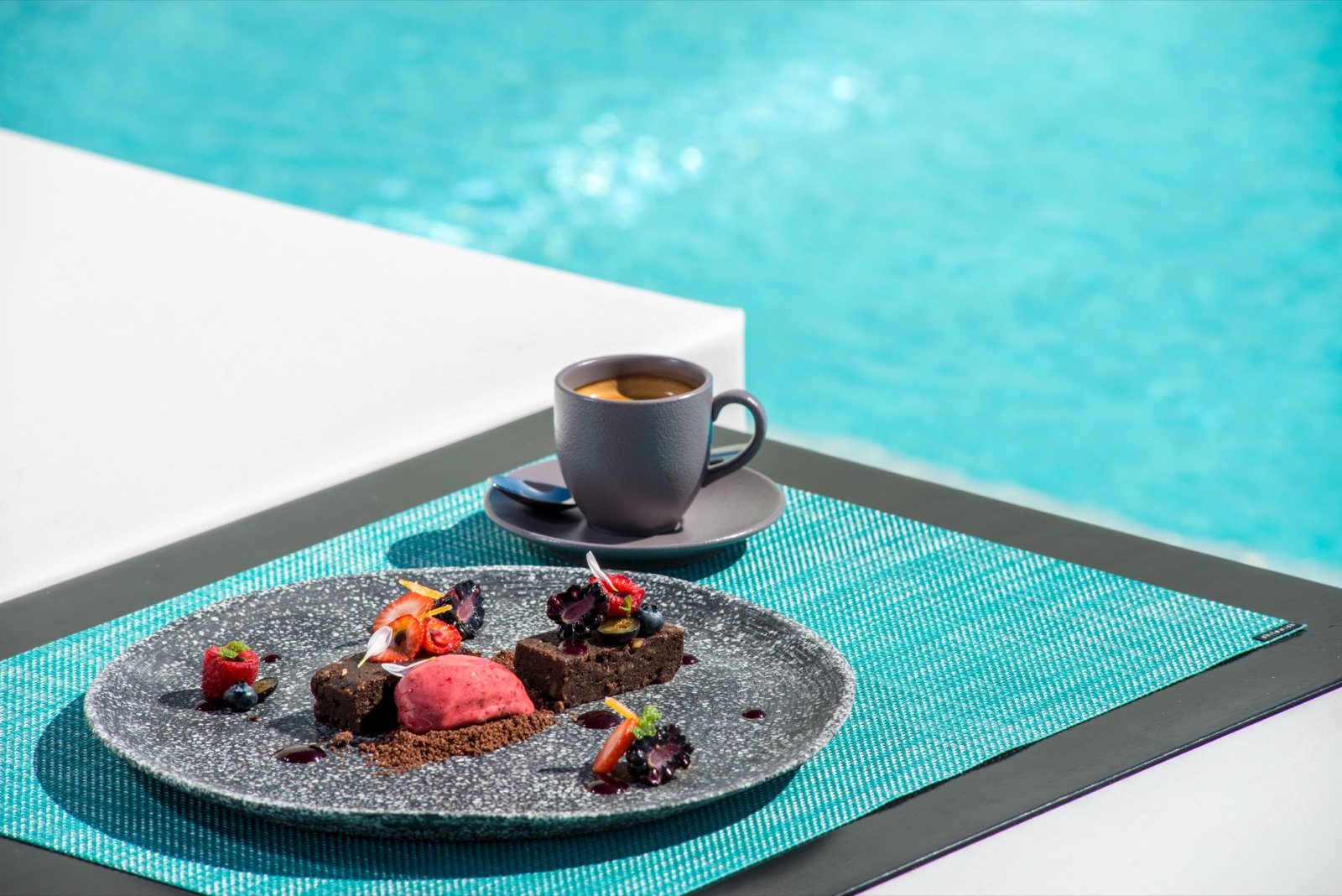 Postre de chocolate y frutos rojos con café junto a la alberca