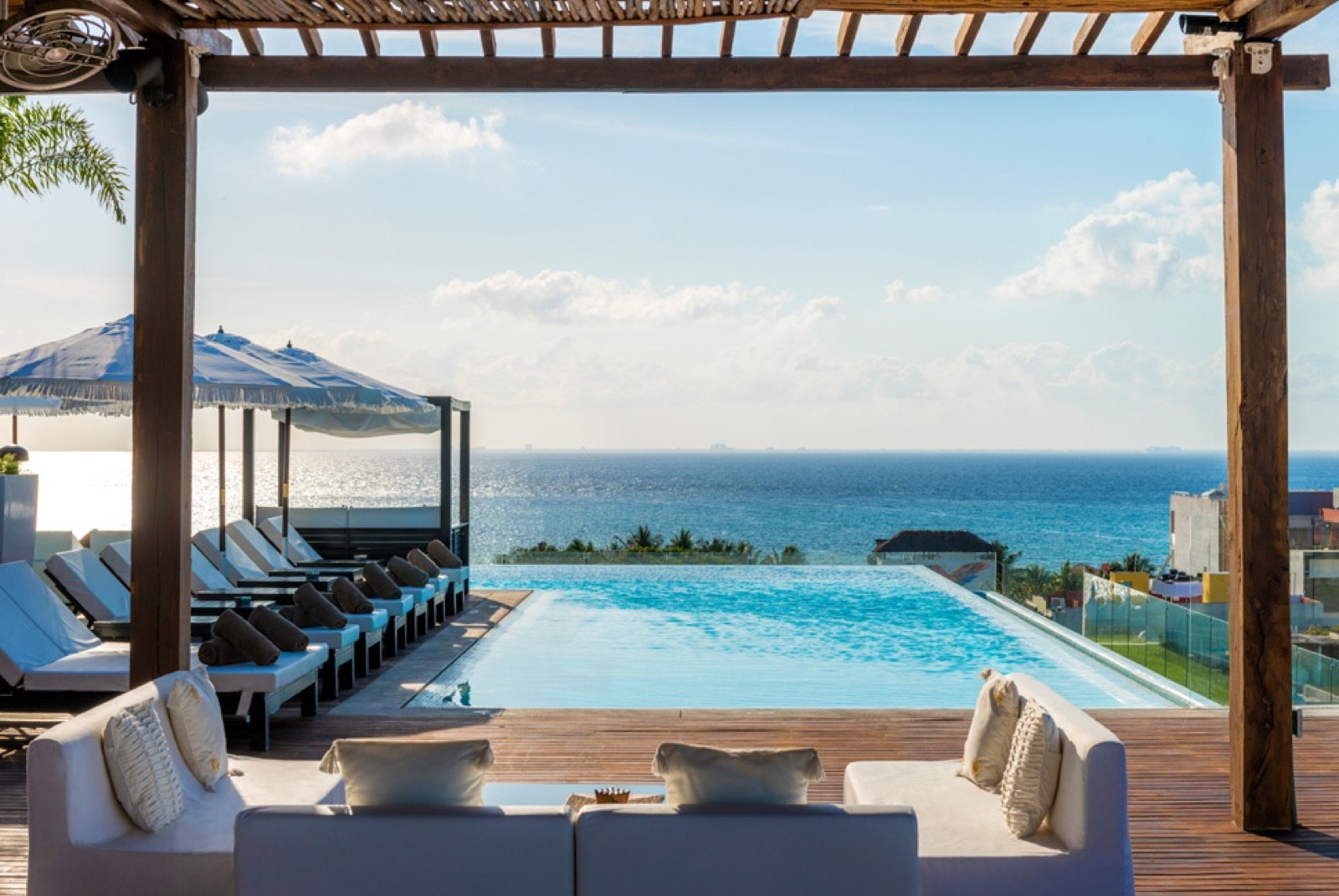 La alberca infinita del rooftop, con palapas, camastros y el mar Caribe al fondo