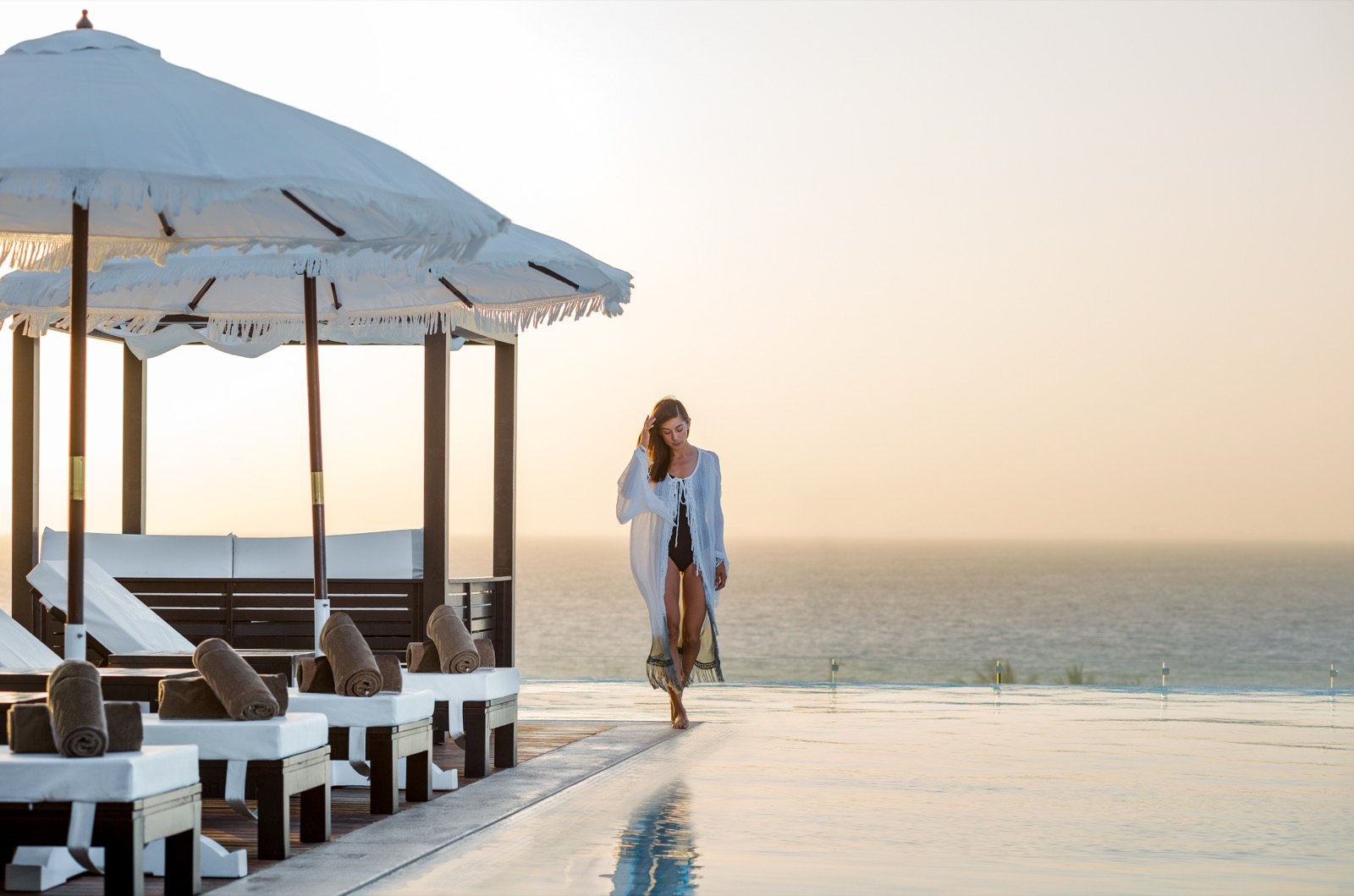 Camastros con sombrillas en el rooftop al atardecer, con el mar en calma