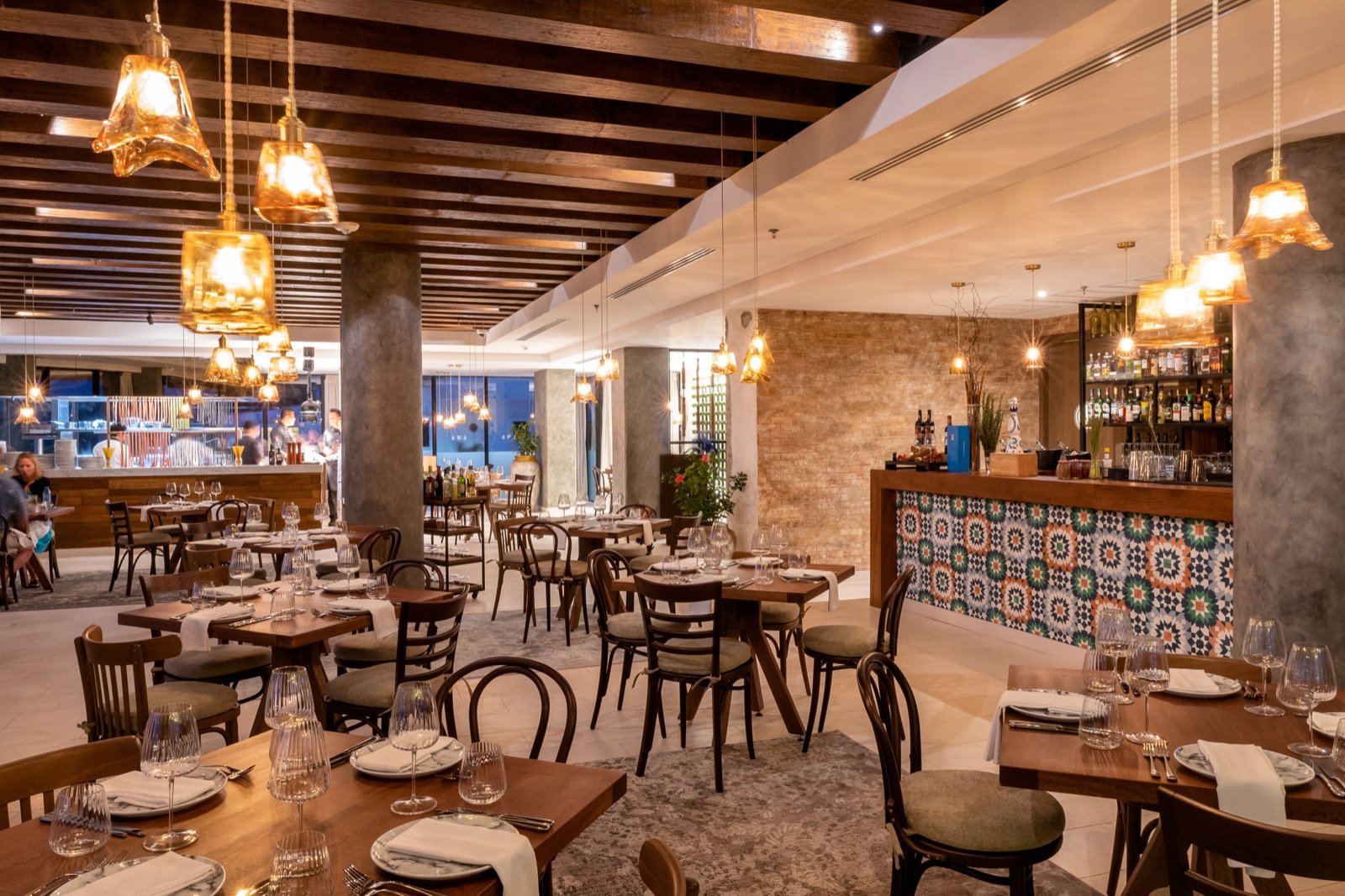 El comedor de Al Mare con lámparas cálidas y mesas de madera