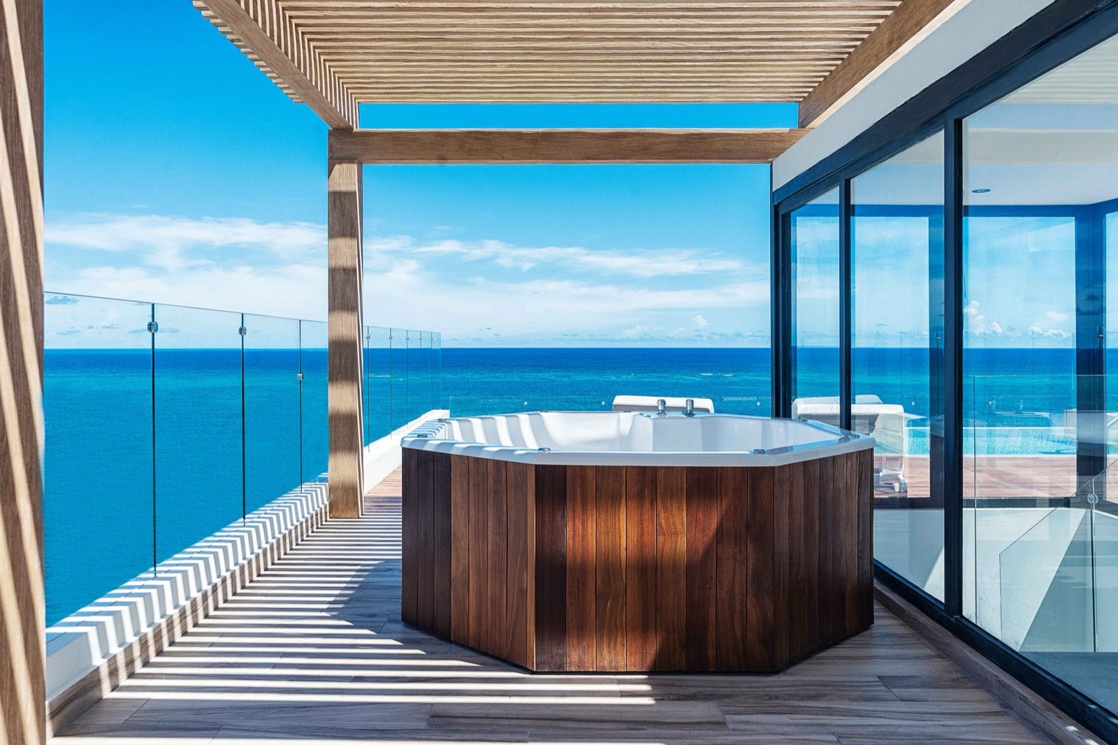 Jacuzzi en un balcón con el mar turquesa enfrente
