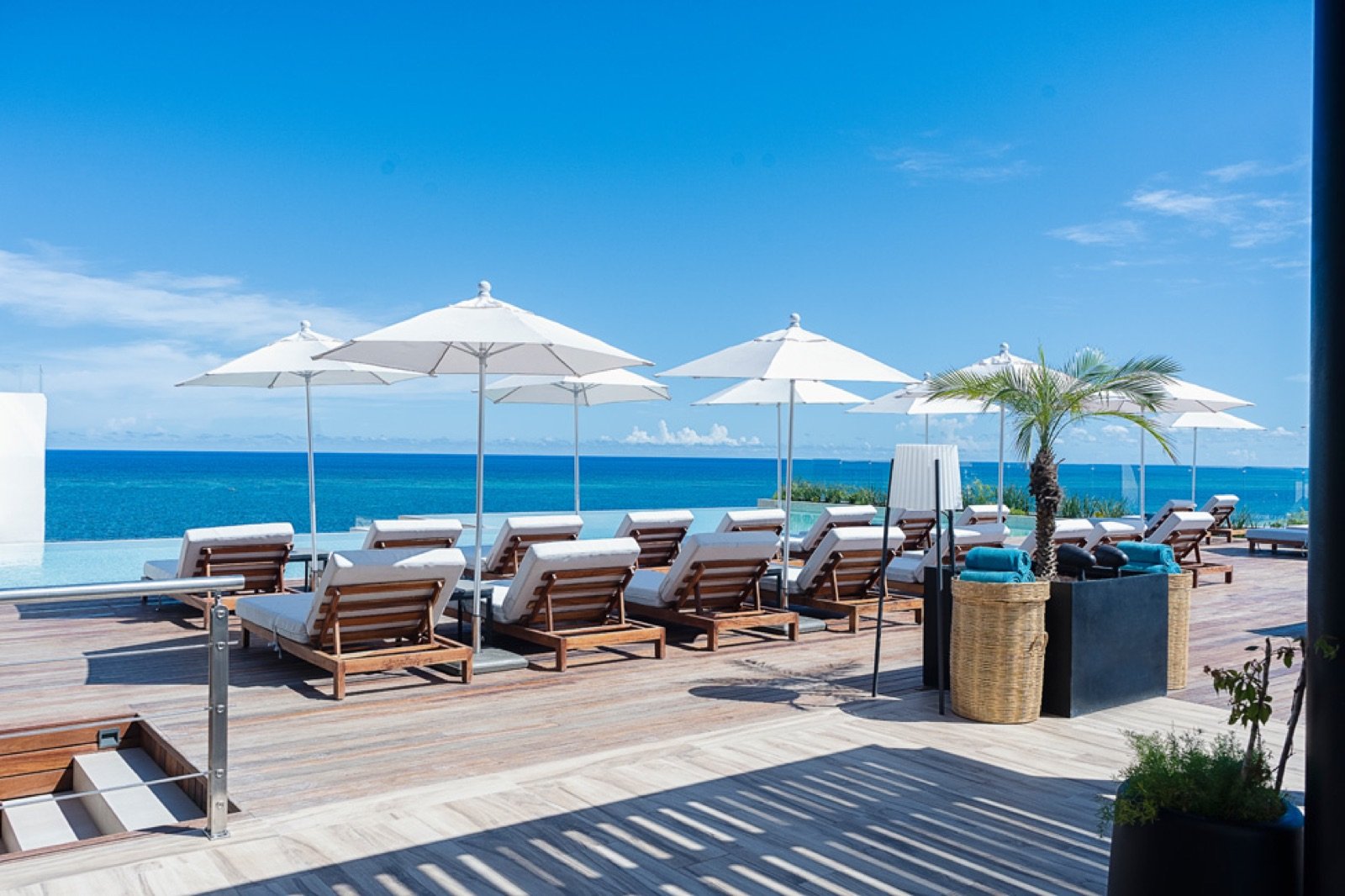 El rooftop con camastros, sombrillas blancas y el mar al fondo