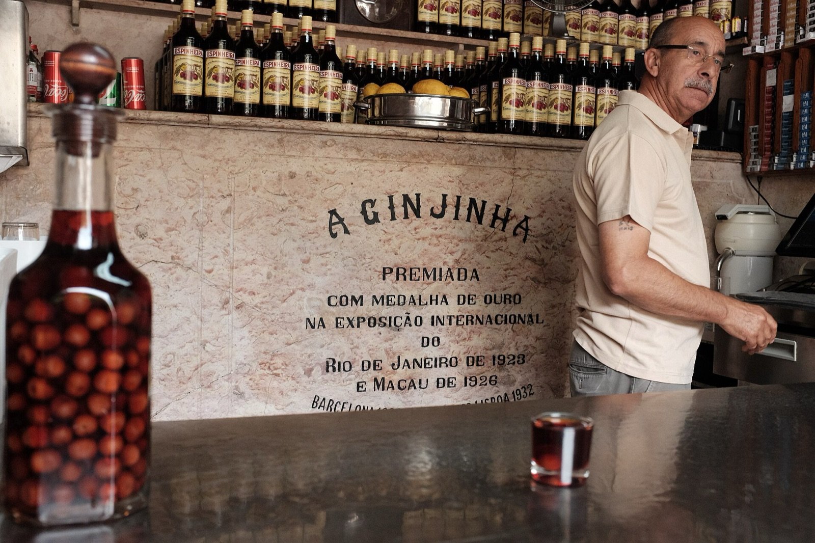 La barra de A Ginjinha, con una botella de licor con guindas y un vasito servido