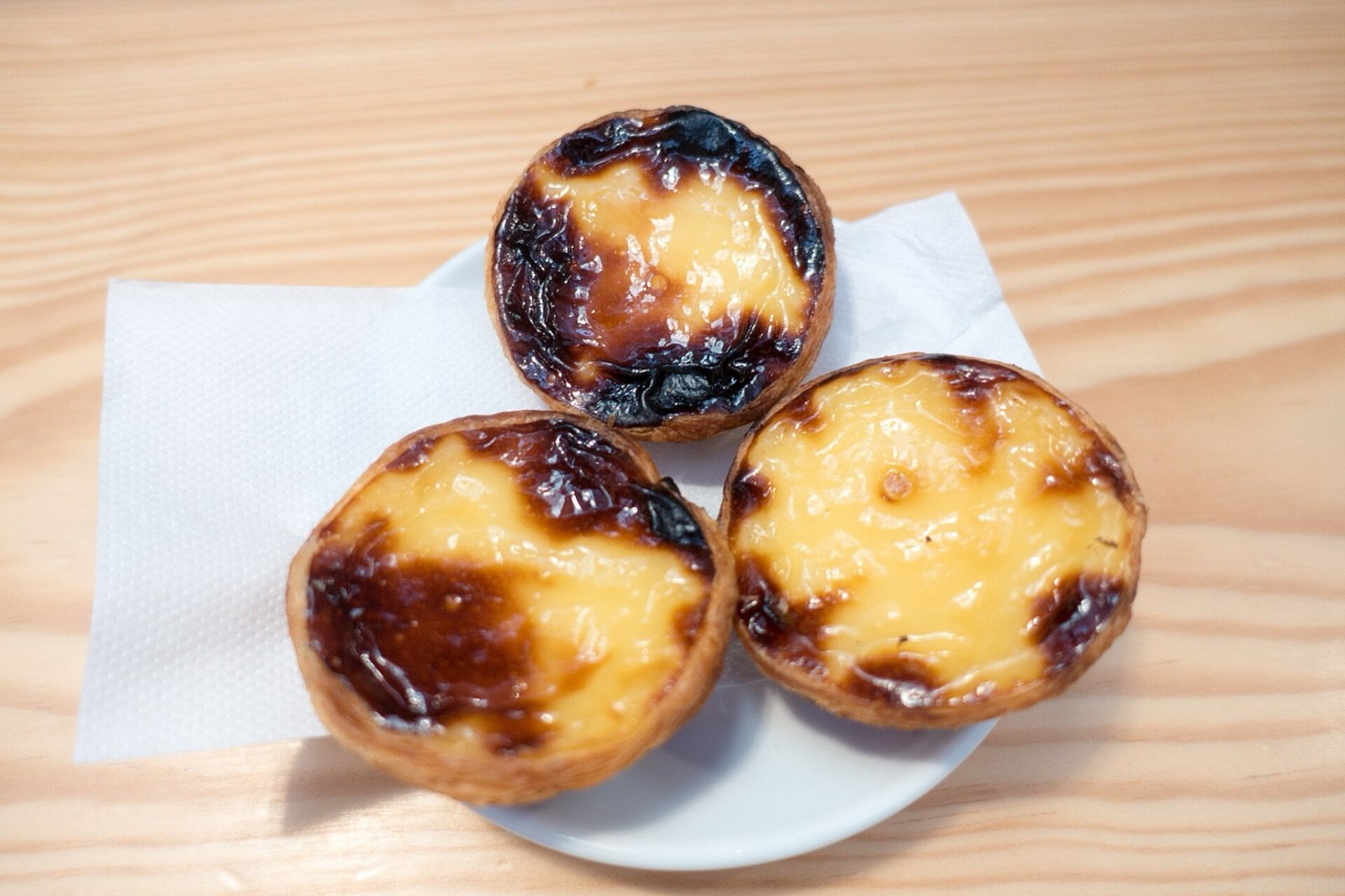 Tres pasteles de nata de Manteigaria, recién horneados, sobre una servilleta