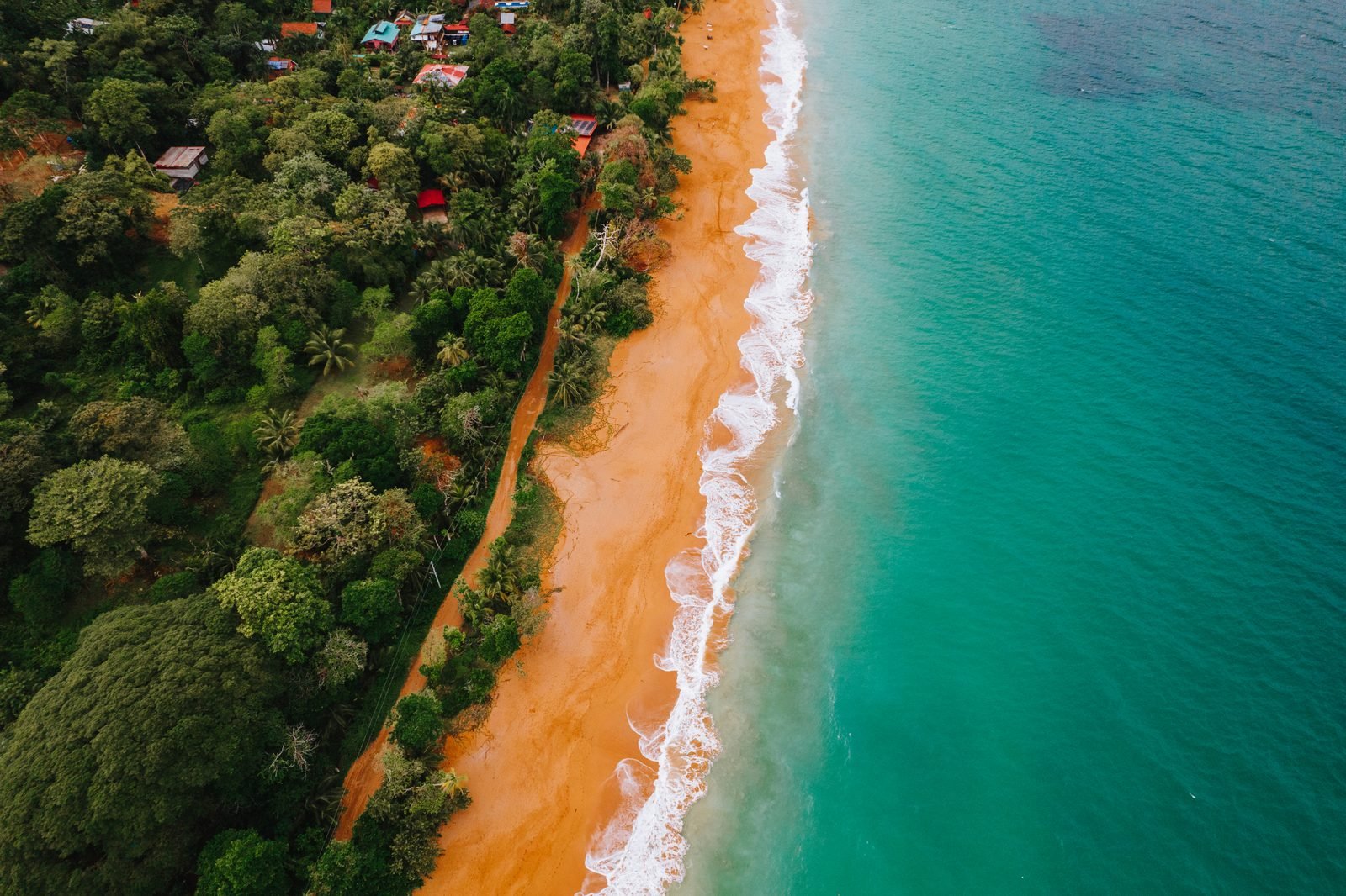 Playa Bluff desde el aire: una franja de arena naranja entre la selva y el mar verde