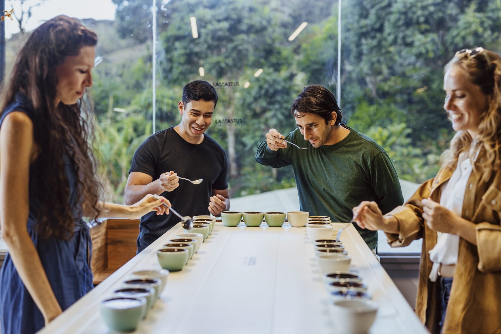 Un grupo hace una cata de café con tazas alineadas sobre una mesa larga en una finca de Boquete
